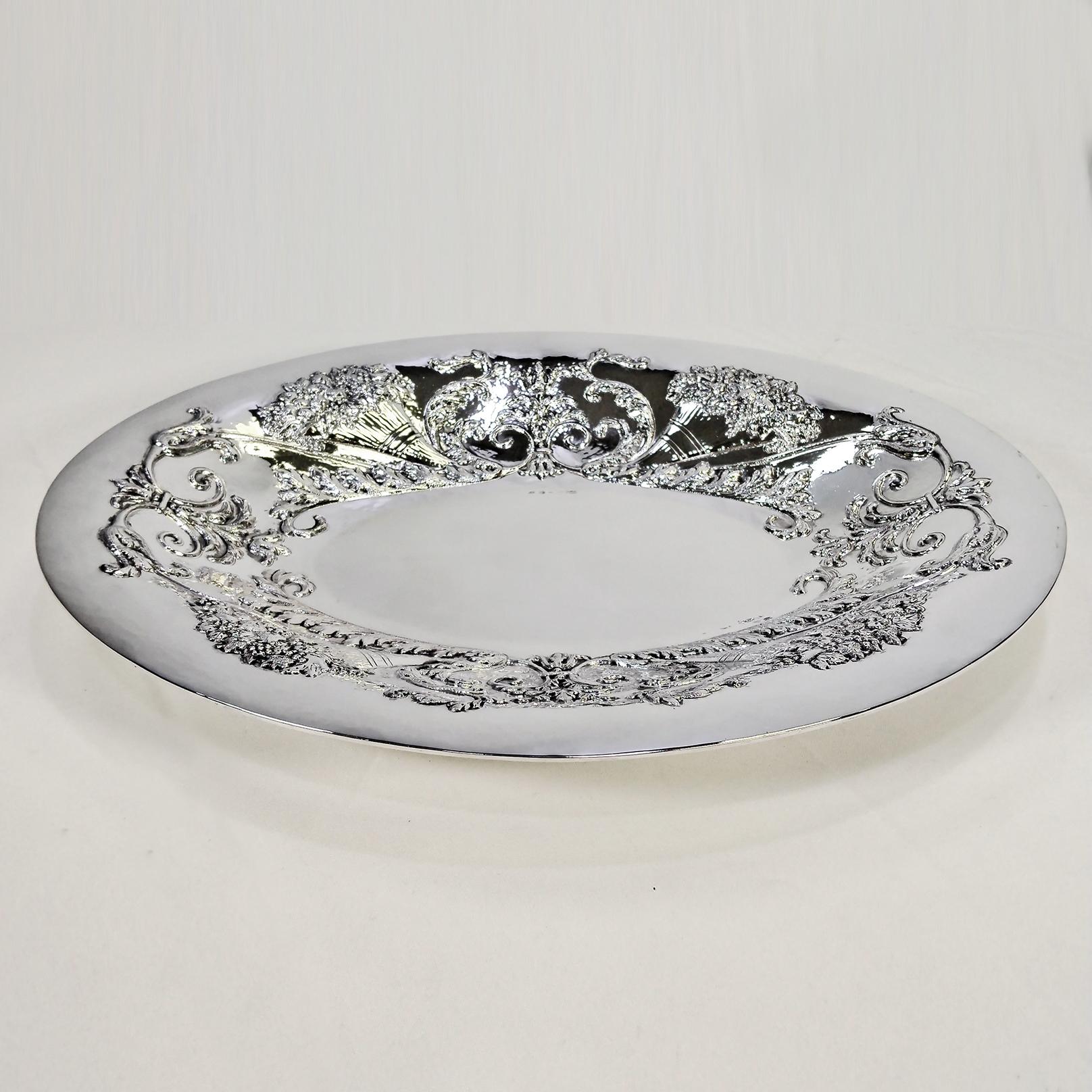 Large centerpiece - oval tray in solid 800 silver.
The centerpiece was made entirely by hand, starting from a rough sheet of 800 silver and then hammered to give it the oval shape with the large raised brim.
The edge was embossed and chiseled to