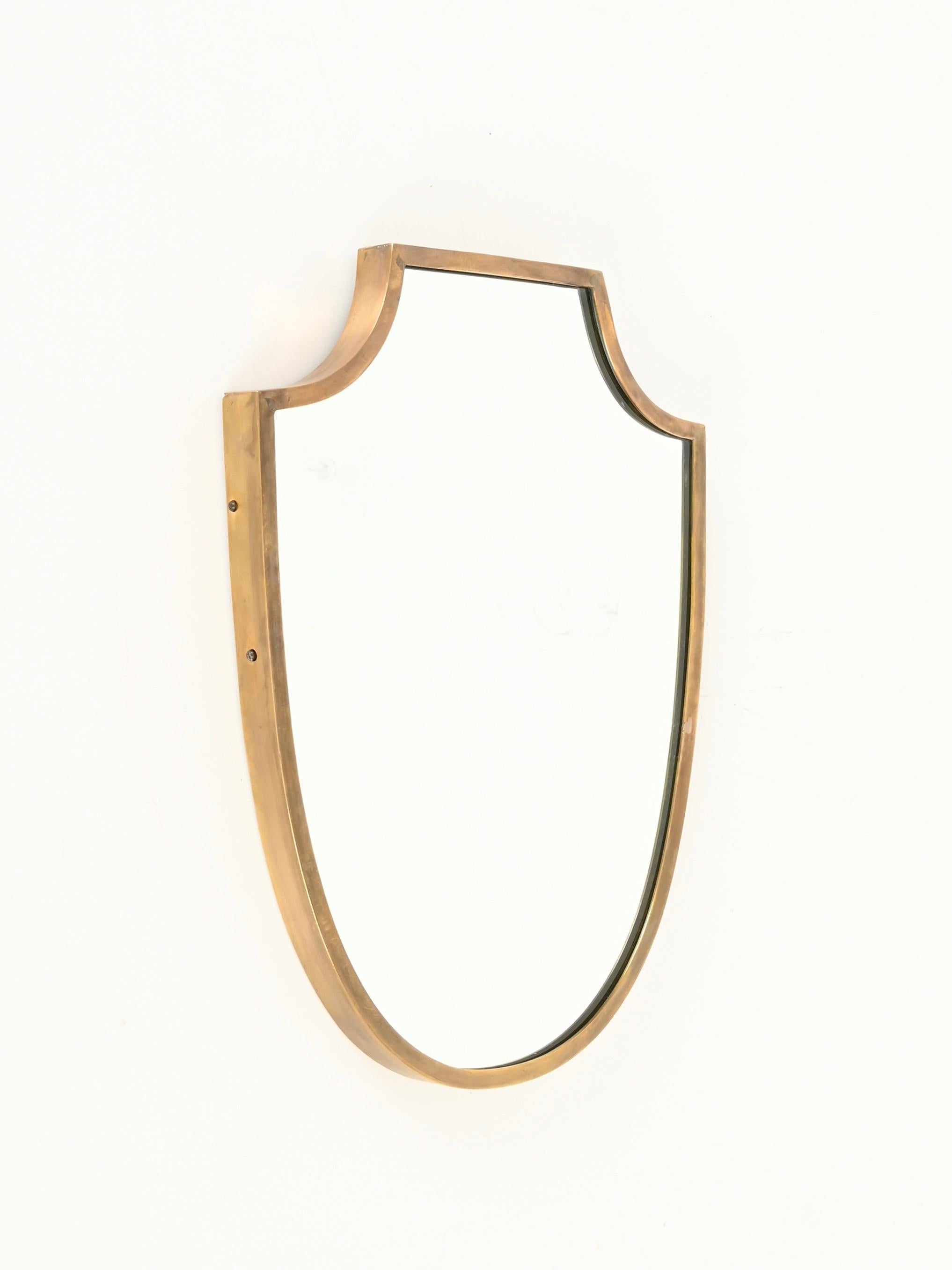 Stunning small shield-shaped mirror with a solid brass frame. This incredibly elegant piece was produced in Italy during the 1950s, and its design is attributed to the mastery of Gio Ponti.

Fully original and in fabulous condition, the mirror