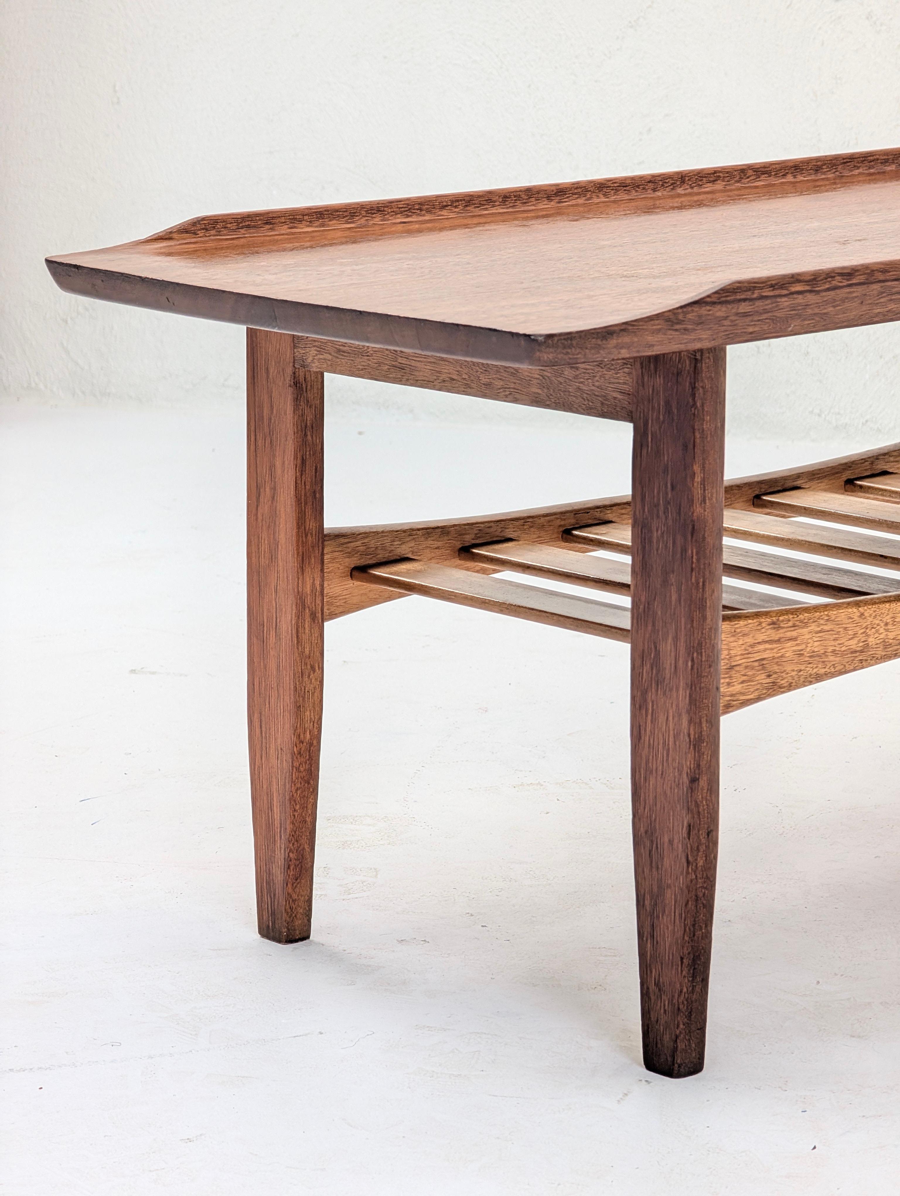 Une table basse rare et exceptionnelle qui incarne l'attrait mondial du design du milieu du siècle, se distinguant par sa construction supérieure en bois massif.

Alors que sa forme évoque la célèbre esthétique du modernisme danois, son histoire est