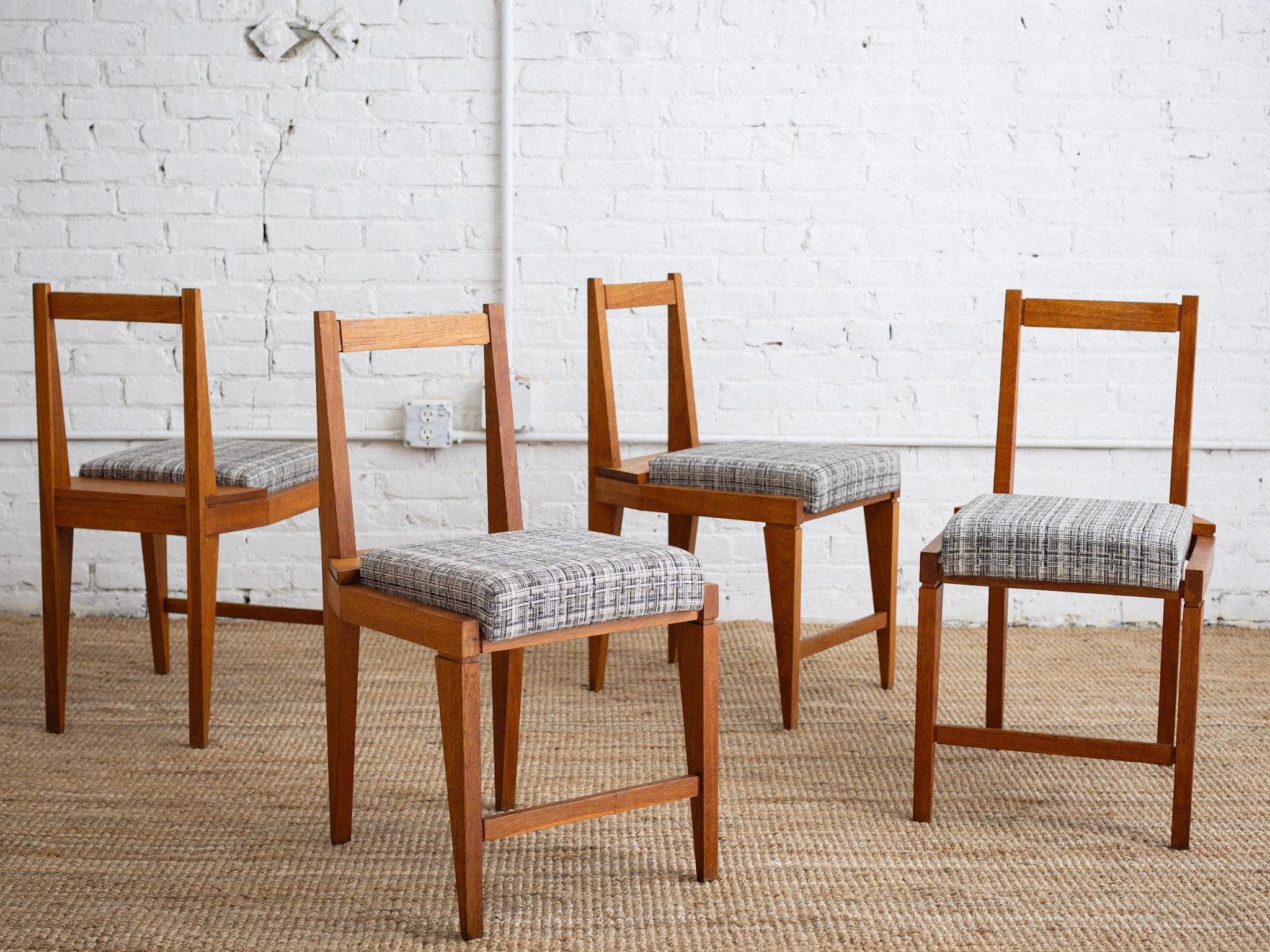 A set of 4 mid century Italian dining chairs. Solid wood frames with a minimalist geometric silhouette. Newer upholstery in a black white and gray woven cotton. Sourced in Northern Italy. 