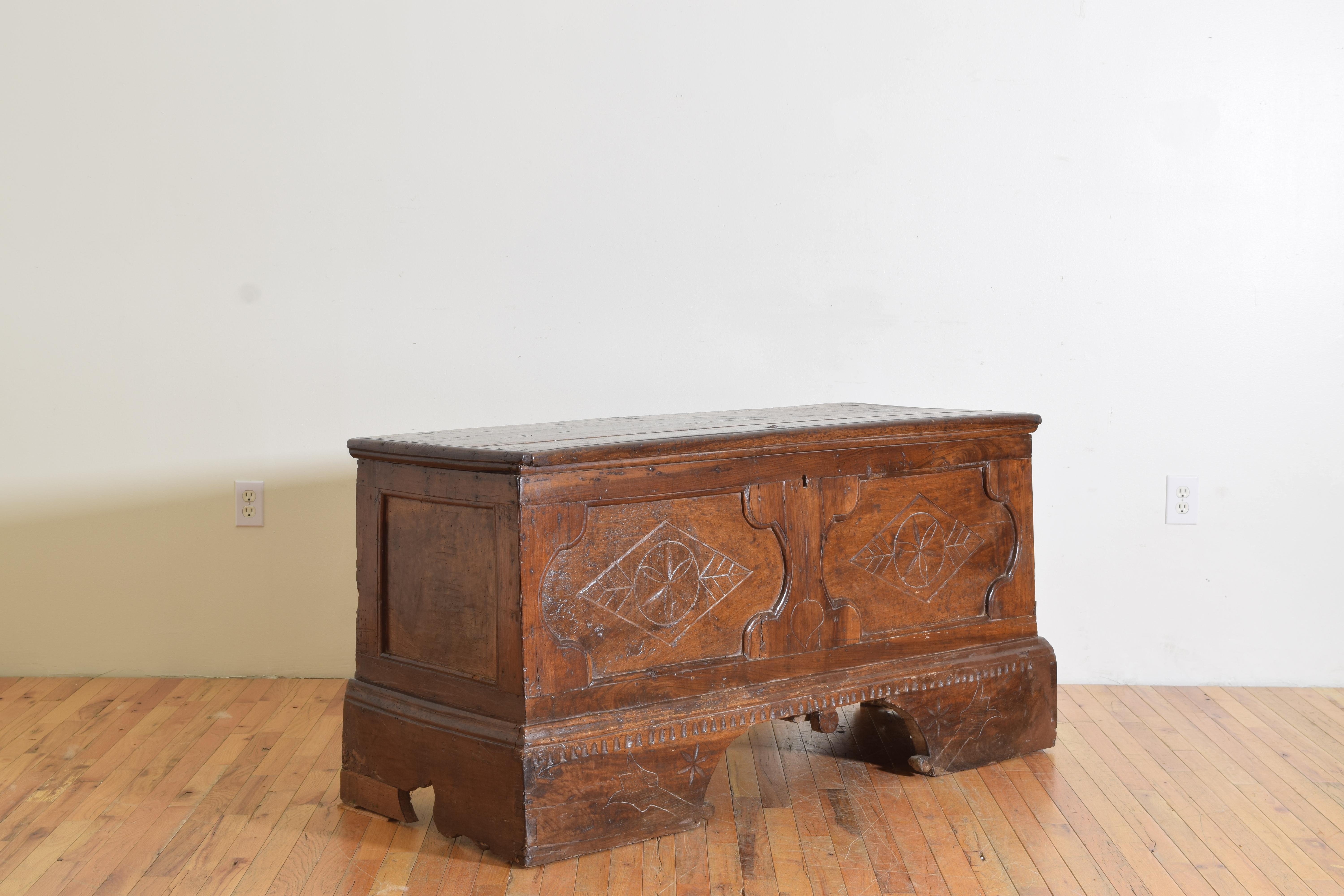Having a molded edge rectangular hinged top above a conforming case housing a large storage area, the case paneled and carved with primitive decorations, raised on large bracket feet