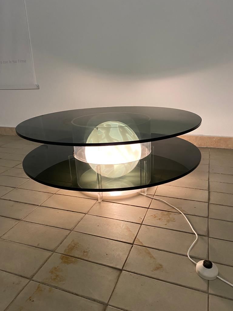 Superbe table basse des années 1970 en verre fumé et plexiglas avec une magnifique boule en verre soufflé de Murano qui s'allume pour créer un effet optique incroyable.