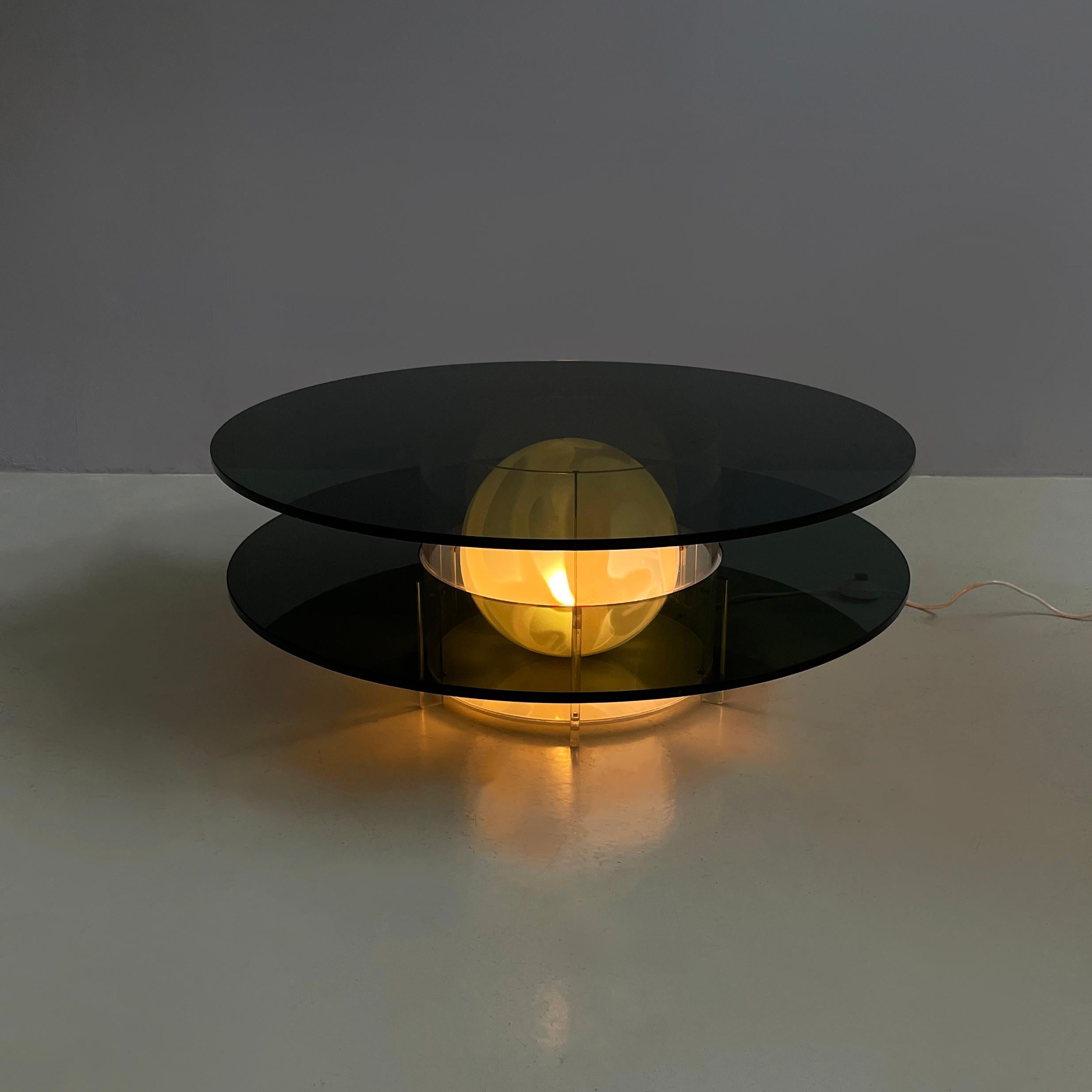 Italienischer Couchtisch aus Rauchglas und Plexiglas im Raumzeitalter mit Lampe, 1970er Jahre
Couchtisch mit Lampe und doppelter runder Ablage aus Rauchglas. Die zentrale Struktur besteht aus einem Plexiglaszylinder, der eine Kugel aus transparentem