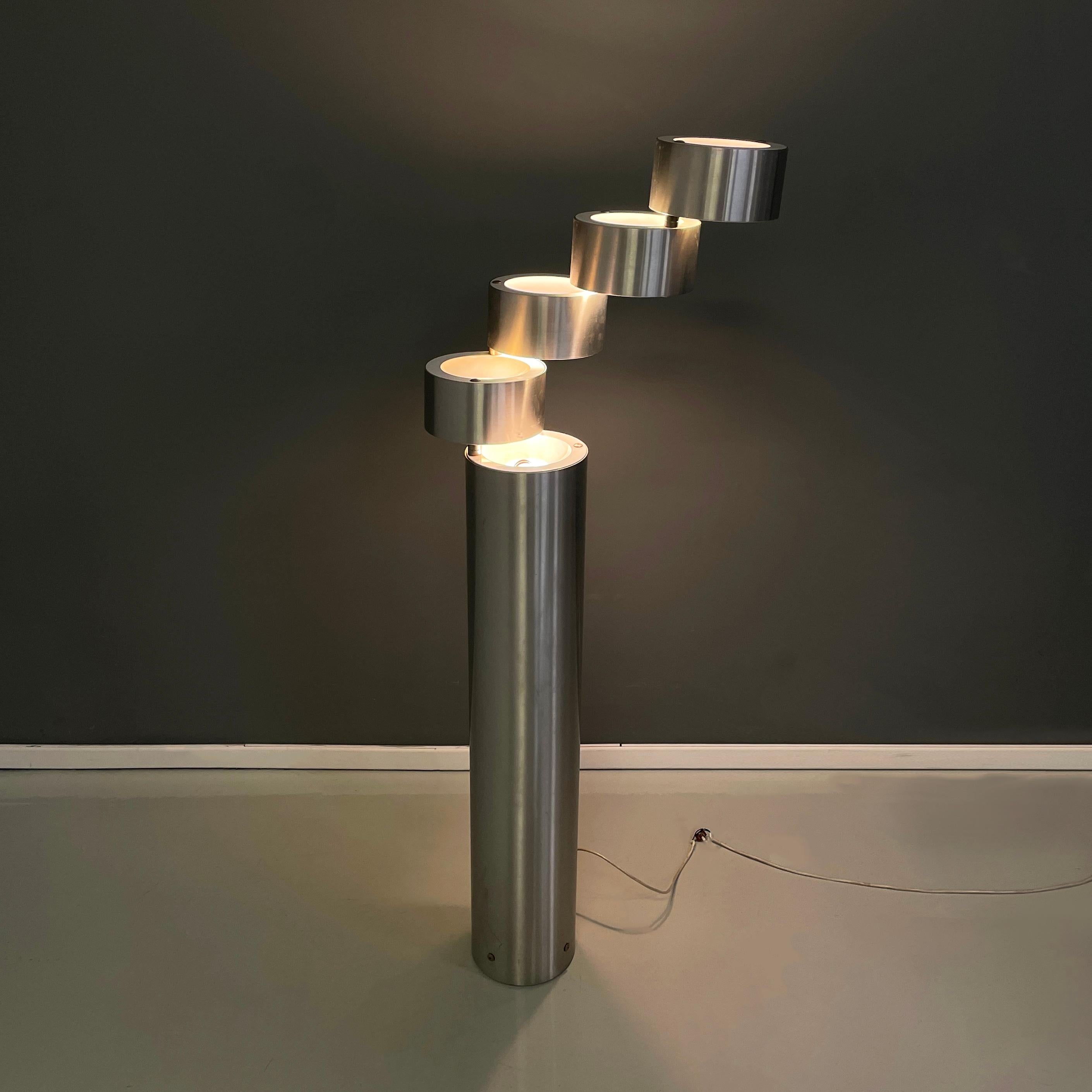 Round base floor lamp with 5 lights, in brushed metal externally and white painted metal internally. The 5 bulbs are distributed, one in the upper part of the base and the other 4 in the 4 cylindrical diffusers, which are joined with round pins