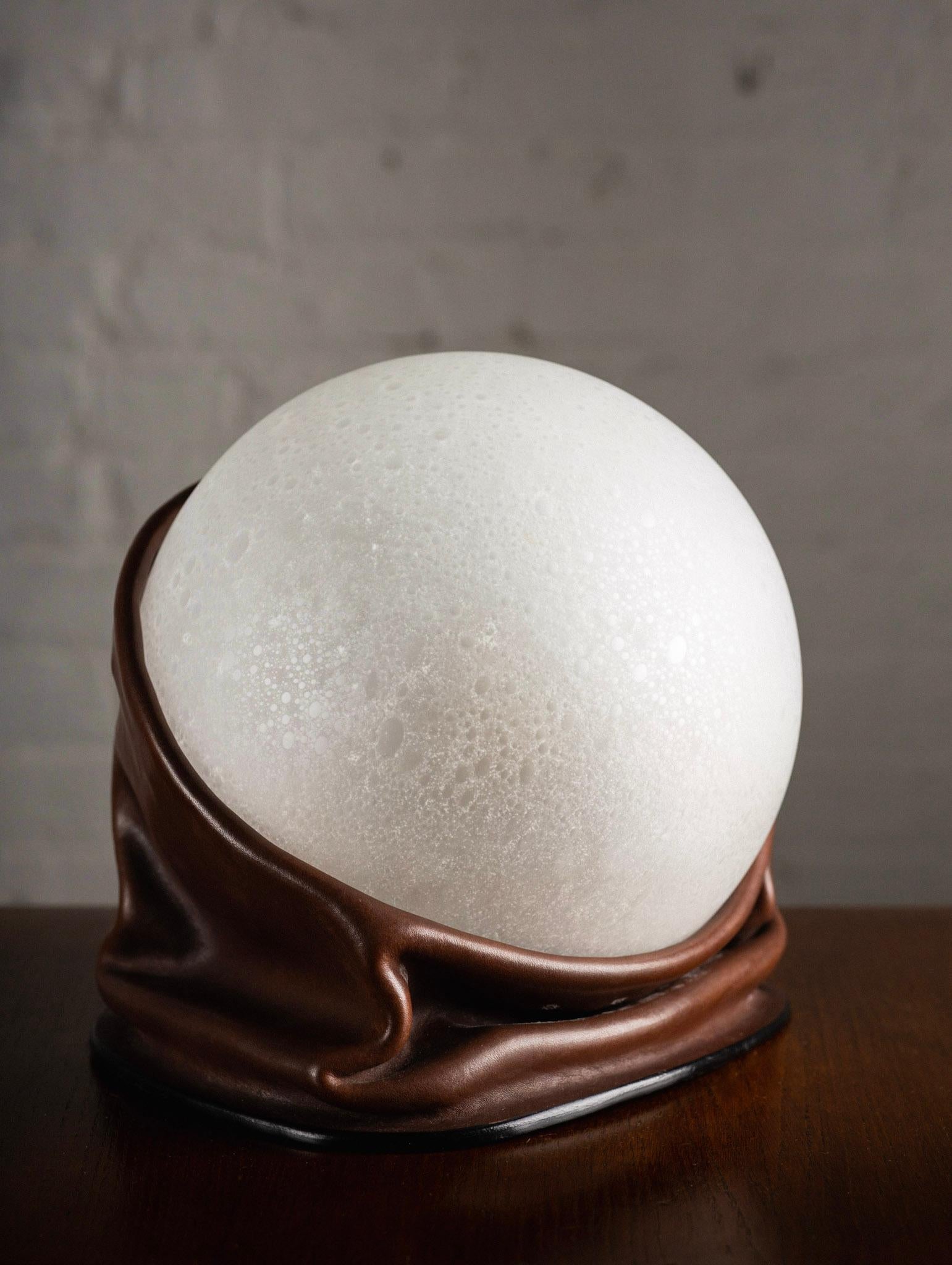 Italian space age leather and glass table lamp. Draped leather base holds a frosted speckled blown glass orb. Signed Nova Tecno. Sourced outside of Florence, Italy.

Orb measures 9” in diameter.