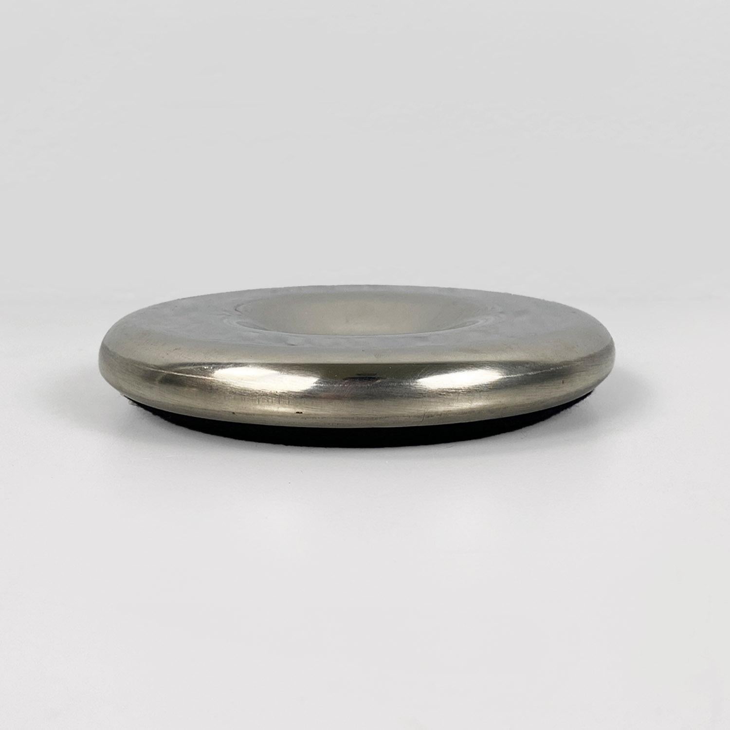 Posacenere rotondo, interamente in acciaio cromato, con pad in tessuto sulla parte di appoggio.
Buone condizioni.
1970s
Misure in cm 13p x 2h
Bellissimo posacenere dalla forma arrotondata, con una vaschetta appena visibile come portacenere e porta