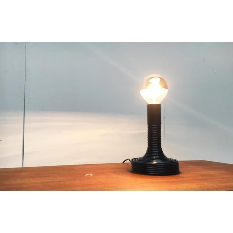 Lampe à poser en spirale du fabricant italien Candle, conçue par Angelo Mangiarotti dans les années 70. Il s'agit ici d'une version rare en bleu foncé.

Le corps forme une Tompetenform qui s'ouvre dans un raccord à vis normal. La source lumineuse