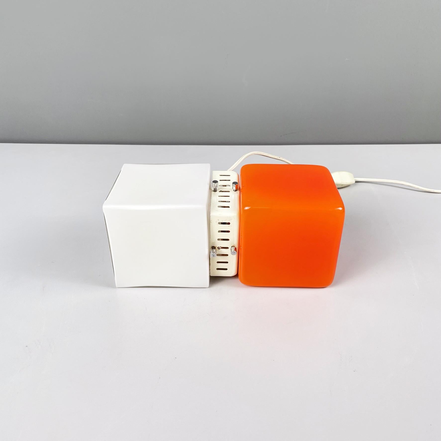 Italian space age Table lamp in orange and opaline glass with white metal, 1970s
Fantastic and vintage table lamp with double square diffuser in opaline glass on one side and bright orange glass on the other. The center is a cream white painted