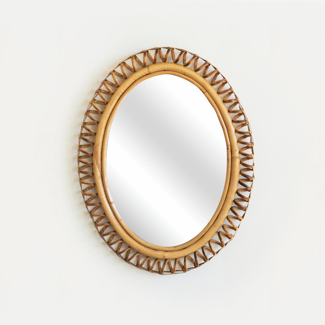 Beautiful small rattan mirror in an oval shape from Italy, 1960's. Unique design with spiral rattan detailing encompassing the mirror. Perfect for powder room. Nice vintage condition.