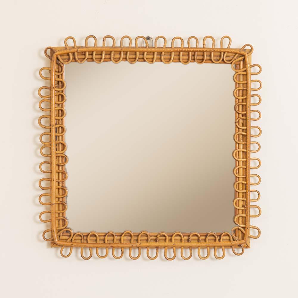 Italian square rattan mirror with looping rattan detail encompassing the mirror. Nice vintage condition with original mirror showing age and patina. Matching pair available.