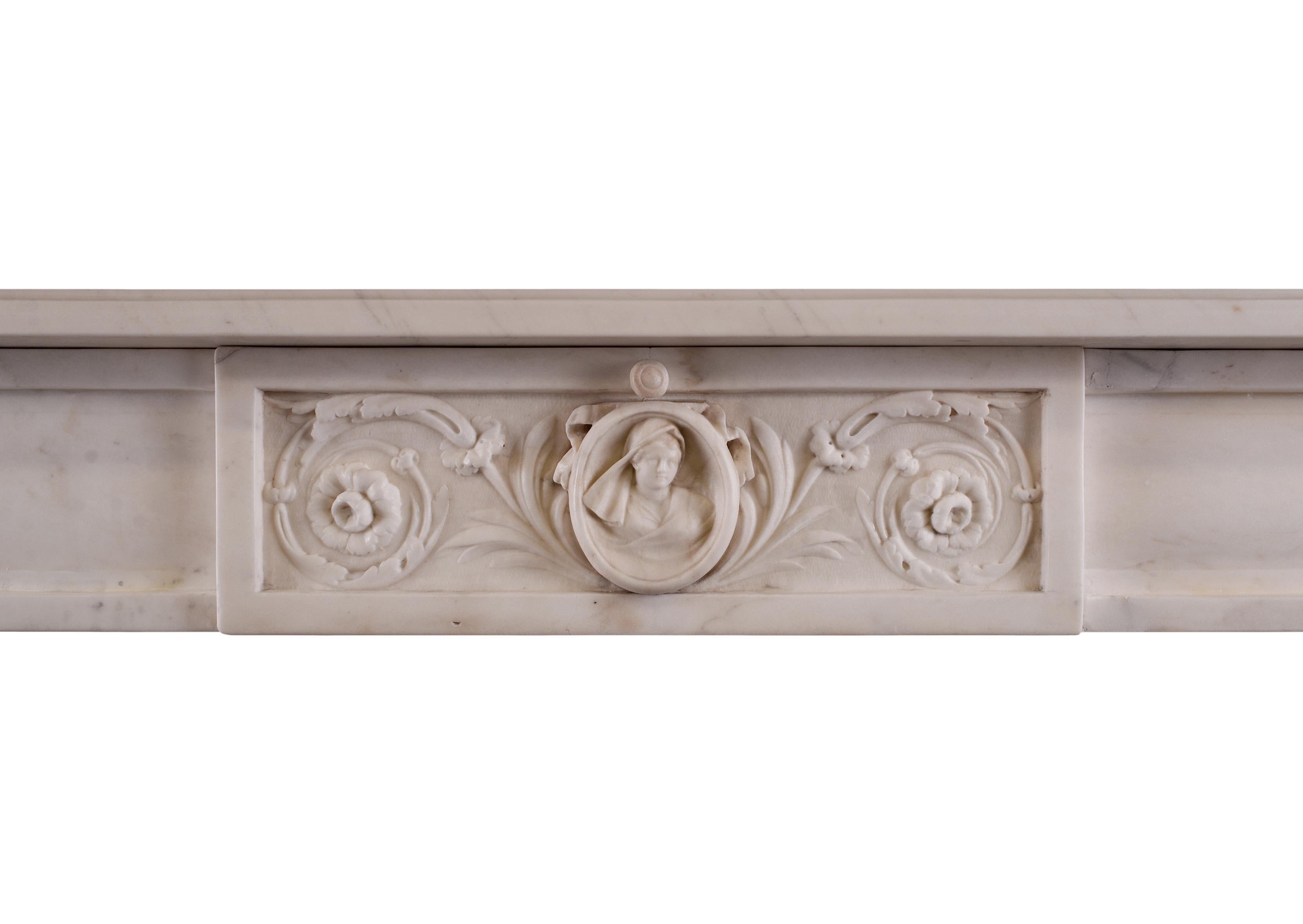 An 18th century Italian fireplace in white Statuario marble. The panelled jambs with carved cascading foliage, surmounted by finely carved rams heads to end blocks. The centre panel with paterae, foliage and female figure to central plaque. Some