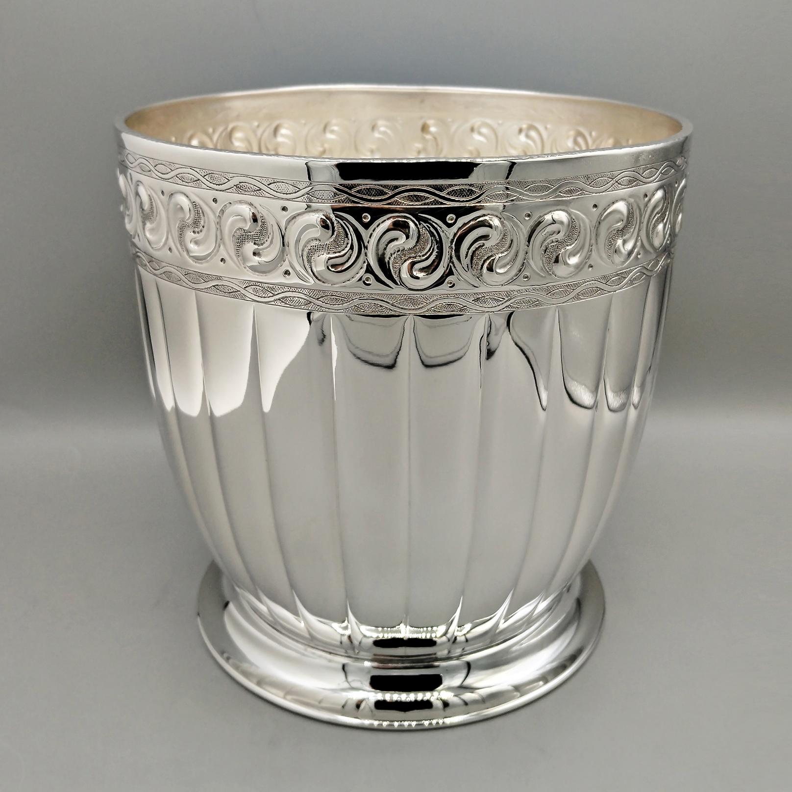 Cubo redondo para champán en plata de ley.
El cuerpo es cilíndrico ligeramente inclinado hacia abajo, donde se ha colocado una base escalonada para garantizar la estabilidad.
La parte central se ha cincelado con líneas, dando a la pieza brillo y