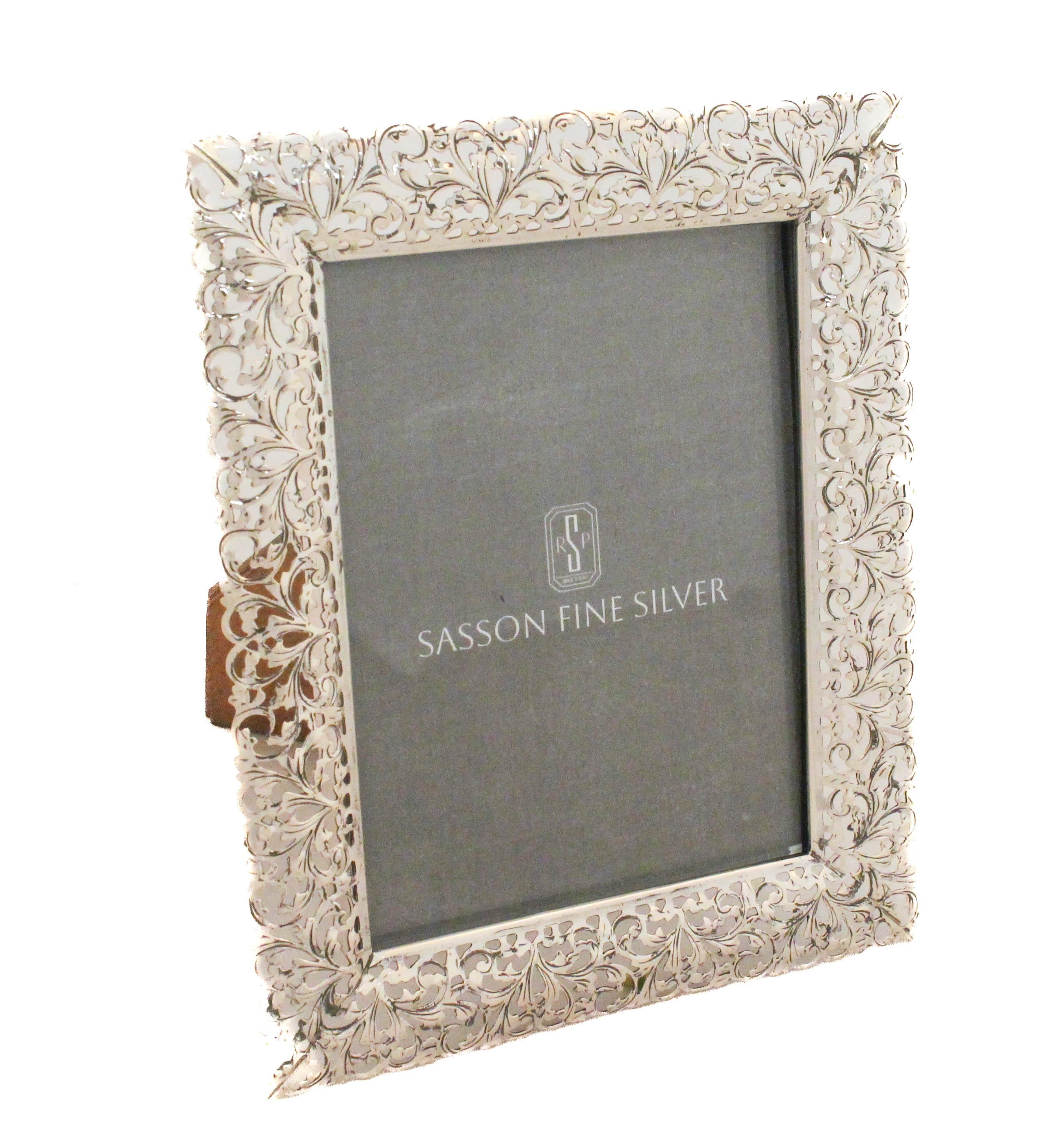 Questa cornice in argento sterling presenta un bordo delicatamente reticolato con motivi di foglie che scorrono, creando un design leggero e arioso dal carattere decisamente femminile. La lavorazione a traforo dell'argento permette un gioco di spazi