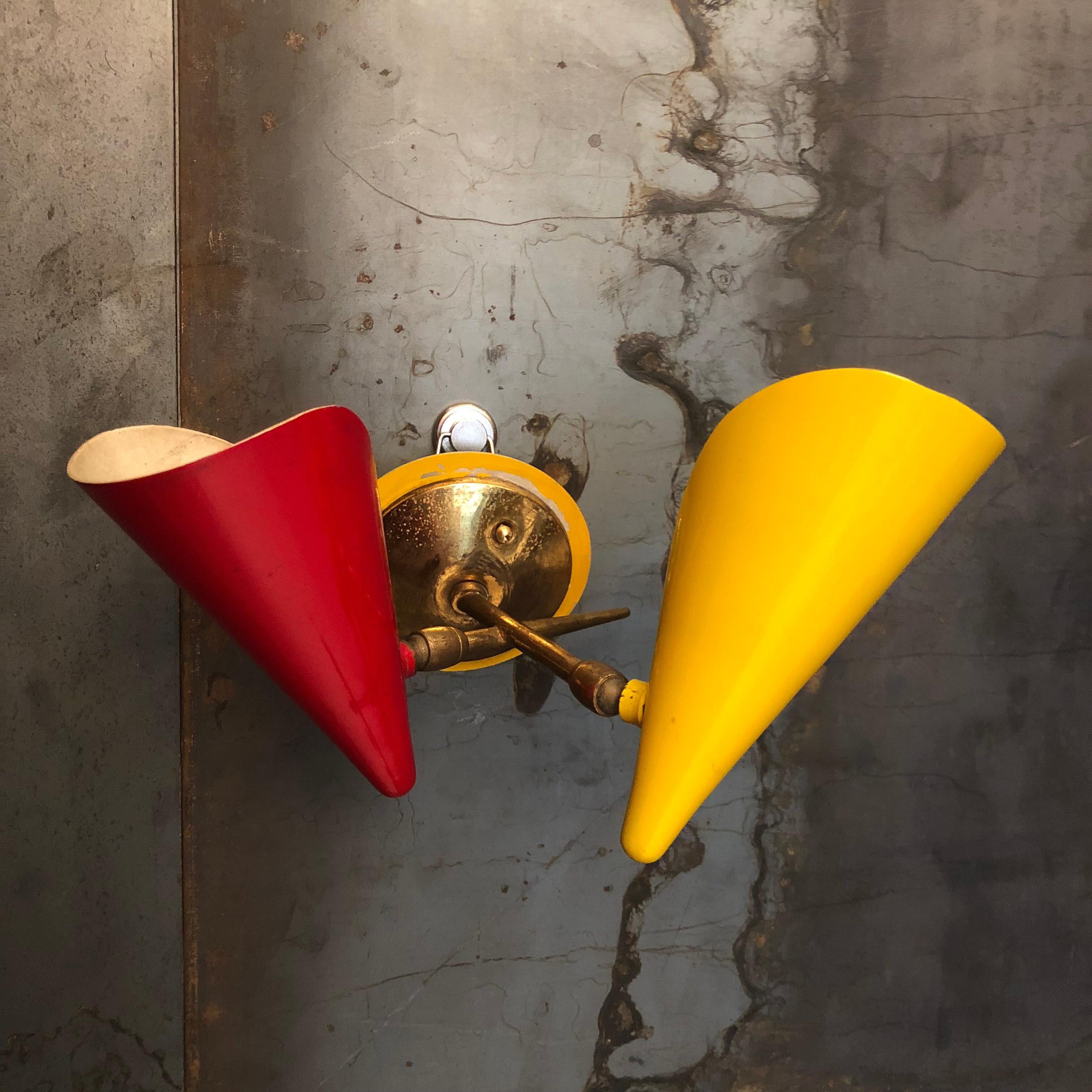 These two double cones sconces by Stilnovo feature brass and lacquered aluminum with original patina. Measures: Height 26 cm, width 25 cm, depth 20 cm. Some loss of lacquer on the base of the brachets, cones in very good conditions.