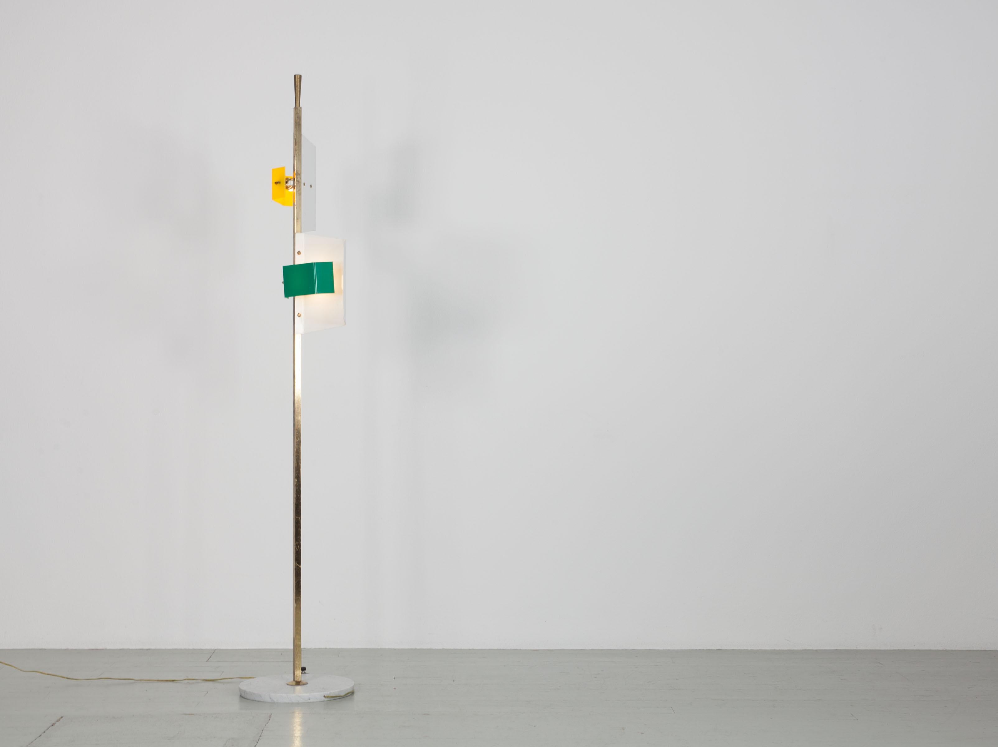 Italian Stilnovo floor lamp from the 50s. The lamp has two lampshades made of white painted metal and one green and yellow plastic element each. The rod of the lamp is made of brass and the base is made of marble. It has two E27 sockets. Except for