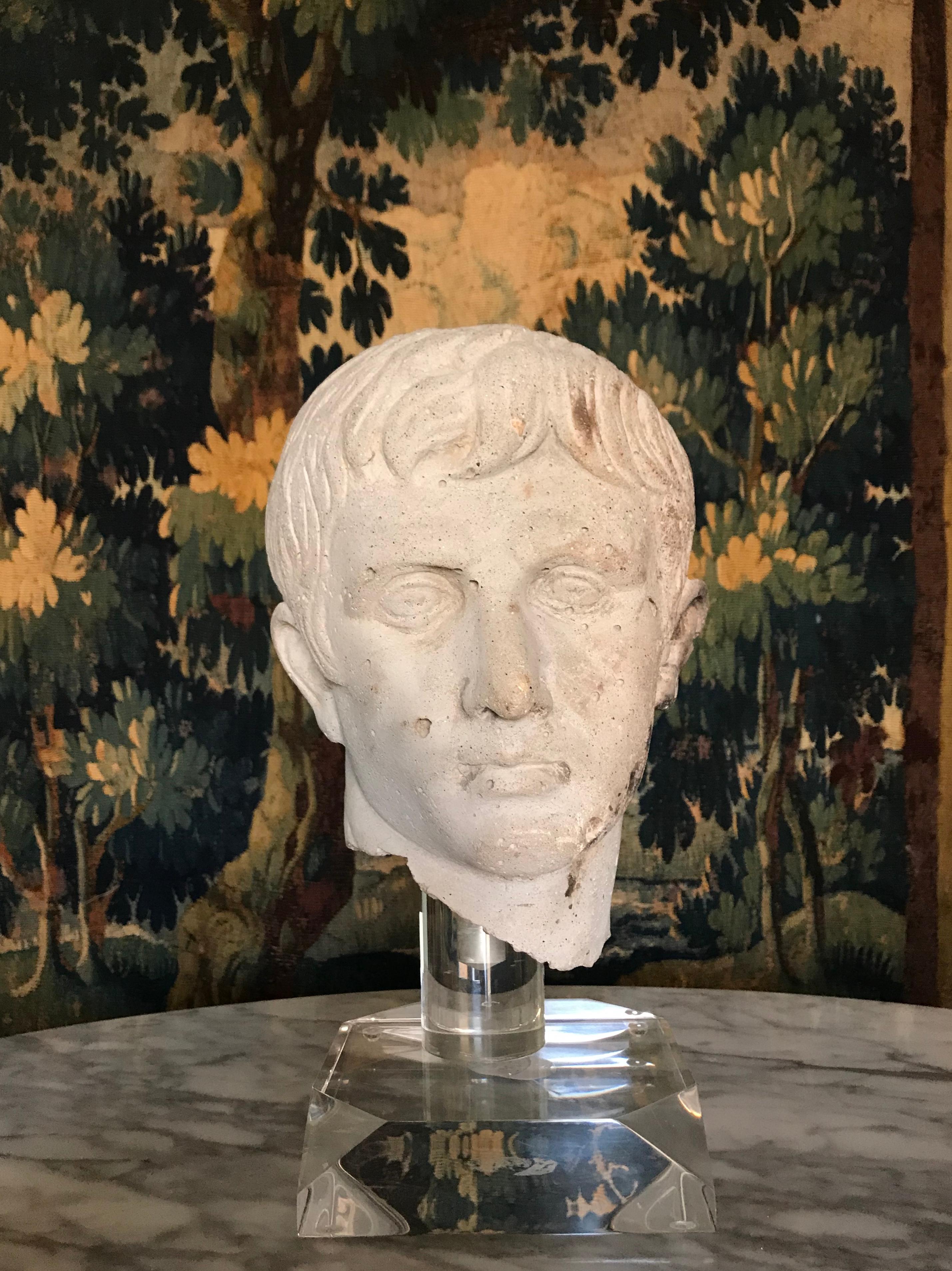 Very decorative bust of Augustus Caesar. Bust is cast stone (concrete), not carved stone and raised on an acrylic base. After the Antique, 20th century rendition. Having rough hewn neck. With pitting/air pockets throughout. Seam from top to back of