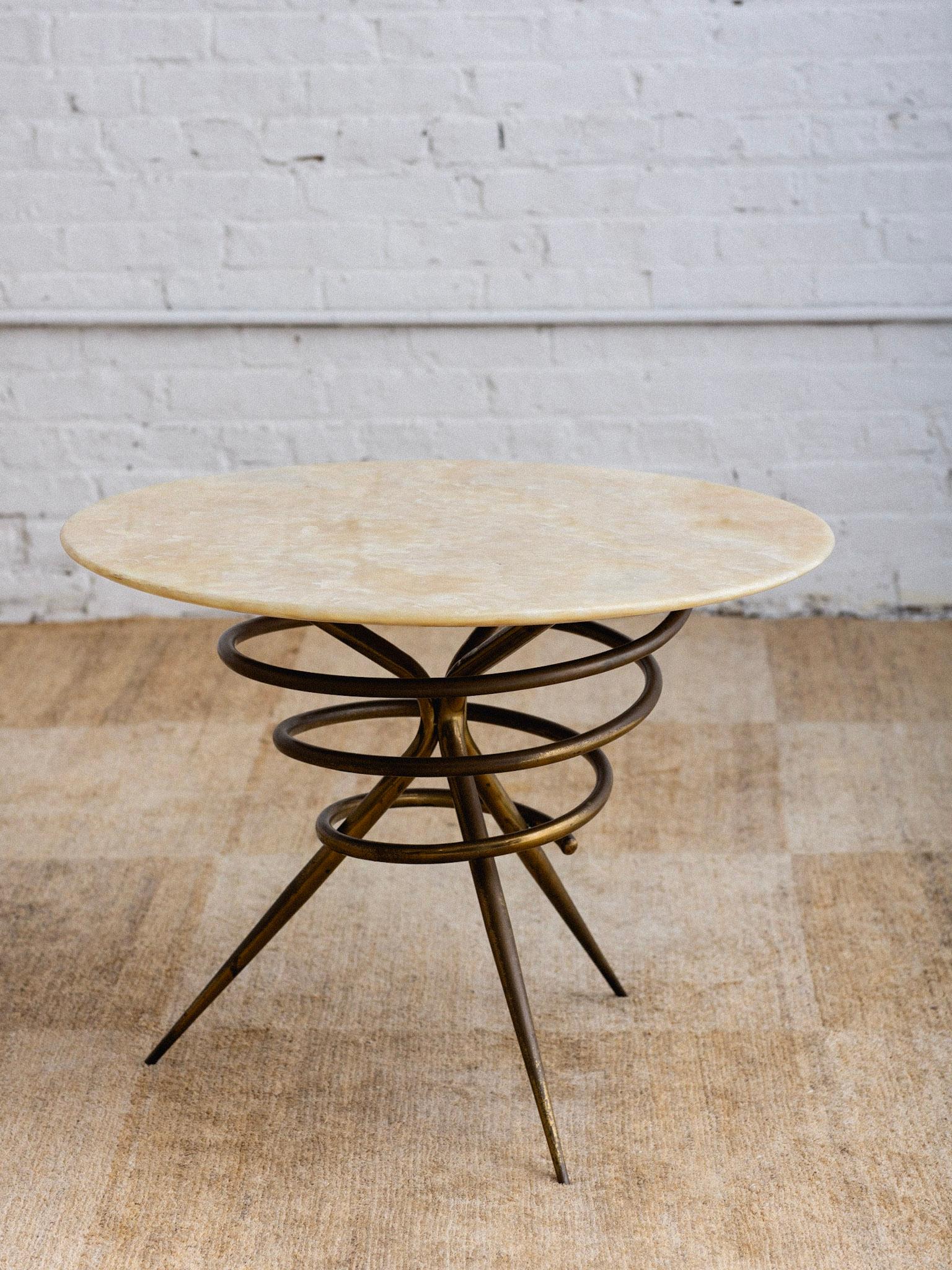 A mid century Italian cocktail table. Tubular spiral form brass base supports the round stone top. Stone exhibits a swirled pattern in warm sand tones, beiges and cream. Brass shows a rich darkened patina. Table top is .5” thick. Sourced in Northern