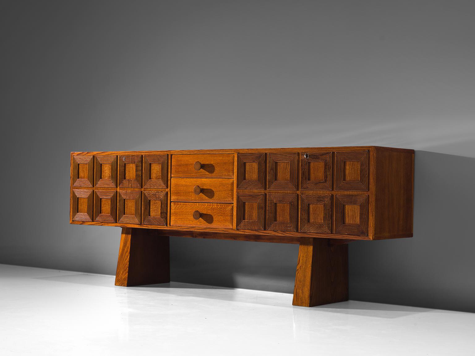 Sideboard, oak, Italy, 1940s.

Delicate and playful Italian cabinet unit in the style of Paolo Buffa on broad, trapezioid legs. The middle section holds three drawers. The piece is robust and features a geometric pattern on the left and right