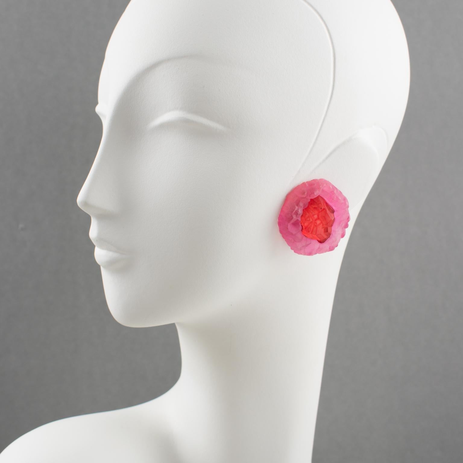 These impressive oversized carved Lucite clip-on earrings are from an Italian design studio. They have a dimensional rounded shape with rock carving in luminous ruby red and bubble gum pink colors in a frosted textured pattern. They are very