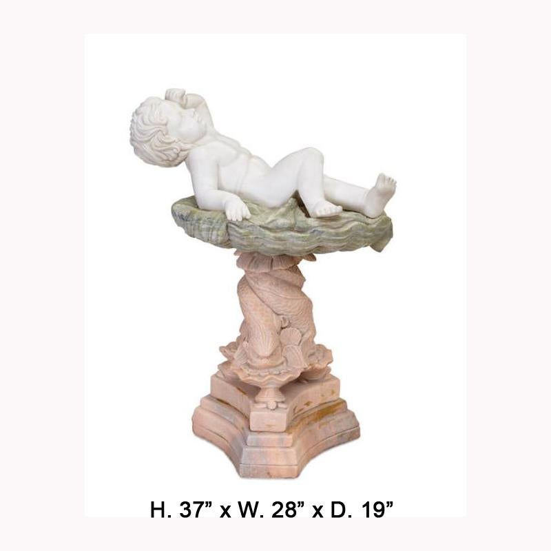 Adorable Italian style carved variegated marble statue.
20th century.

A lovely carved marble baby laying on a foliate-inspired platform, supported by a tripod base depicting three mythical dolphins and turtles, raised on a conforming shaped
