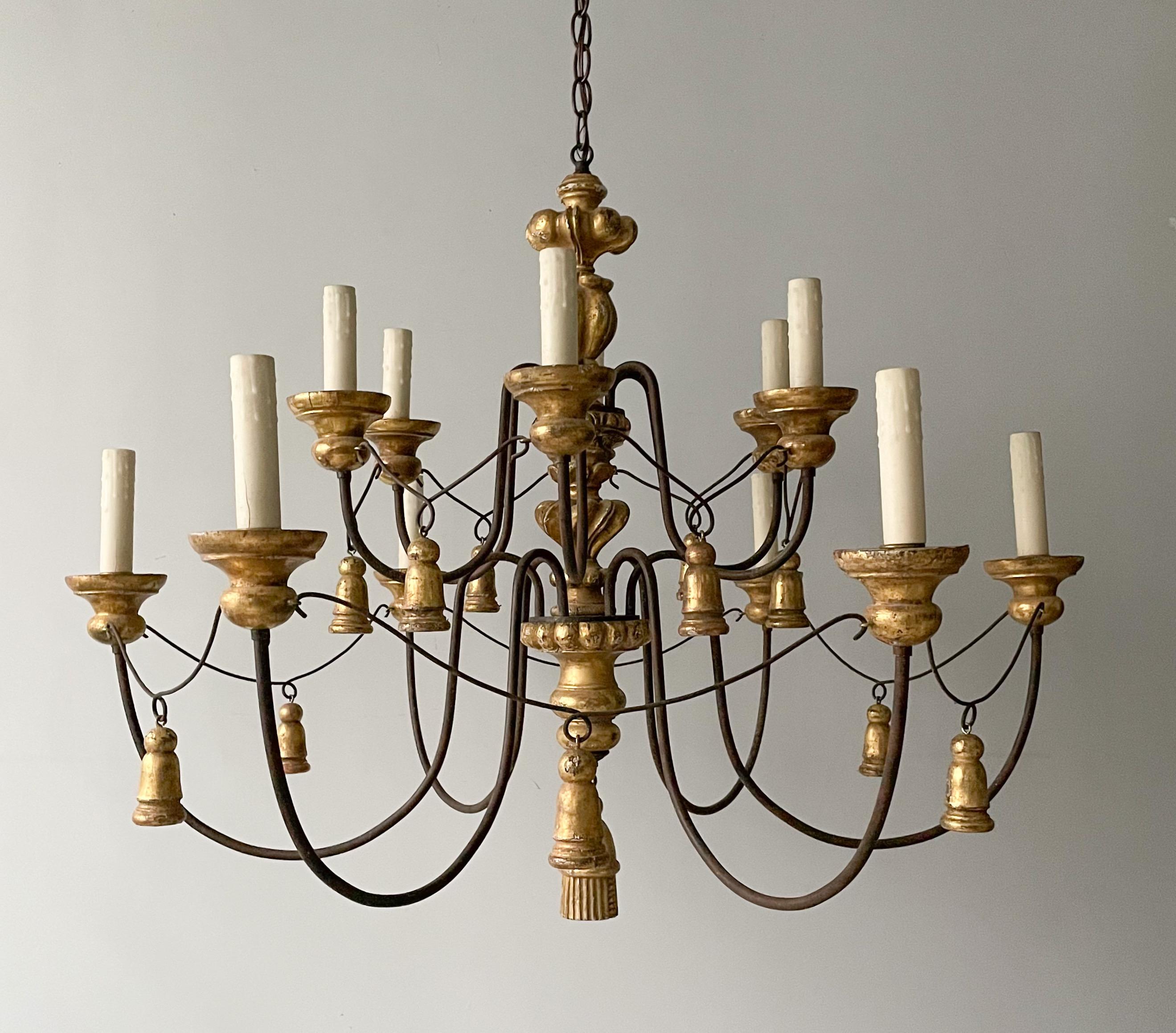 Exquisite, vintage gilt wood and iron “Tassel” chandelier by Paul Ferrante, Los Angeles.

The chandelier features a scrolled-iron, two tier frame in a dark rusty brown finish with gilt wood decorations. 

The chandelier is wired and in working