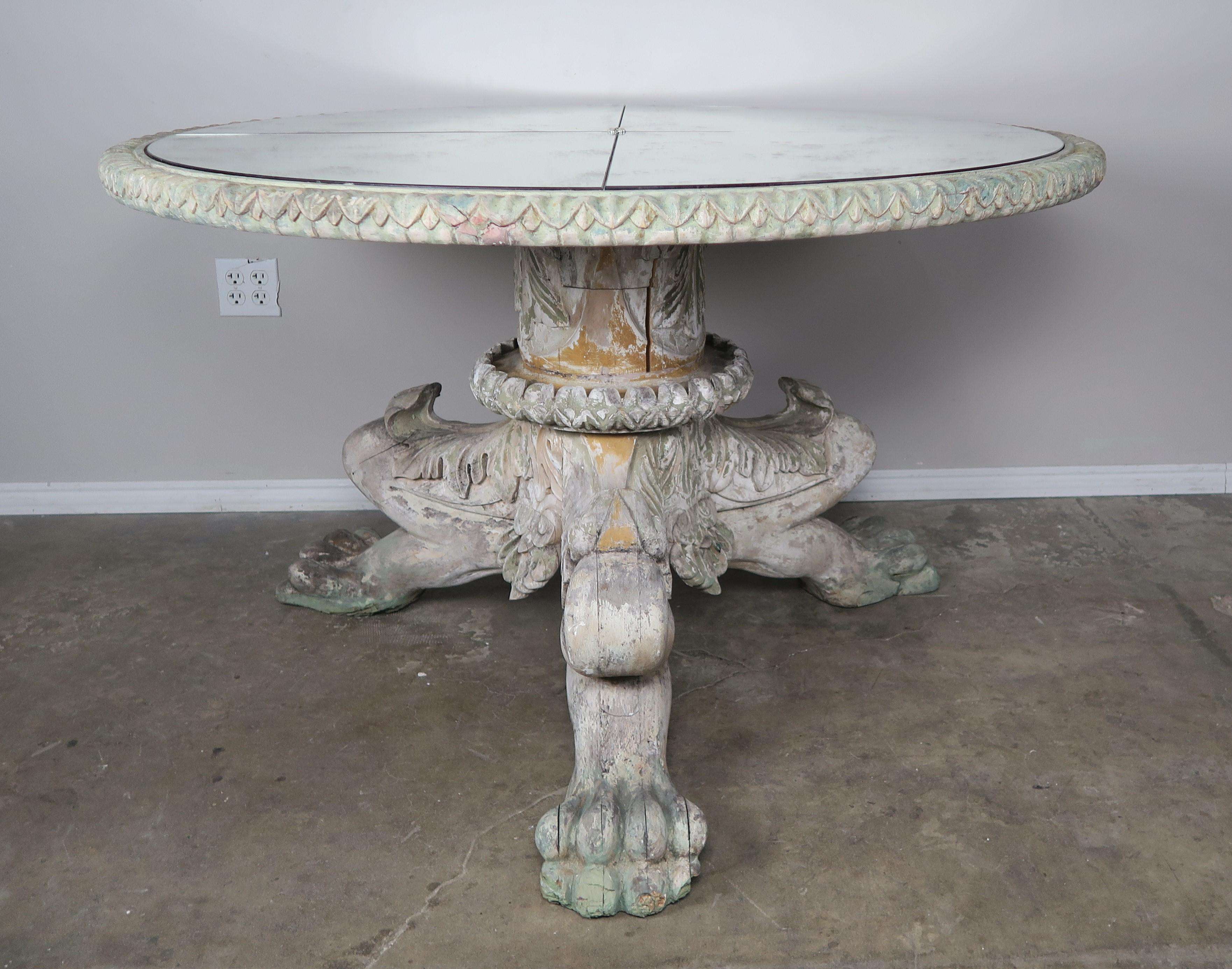 Italian style painted lion paw tripod table with antiqued mirror top. The mirror top is sectioned in four pieces that connect at a center crystal rosette. Worn distressed finish with remnants of paint throughout. Beautiful carved details of acanthus