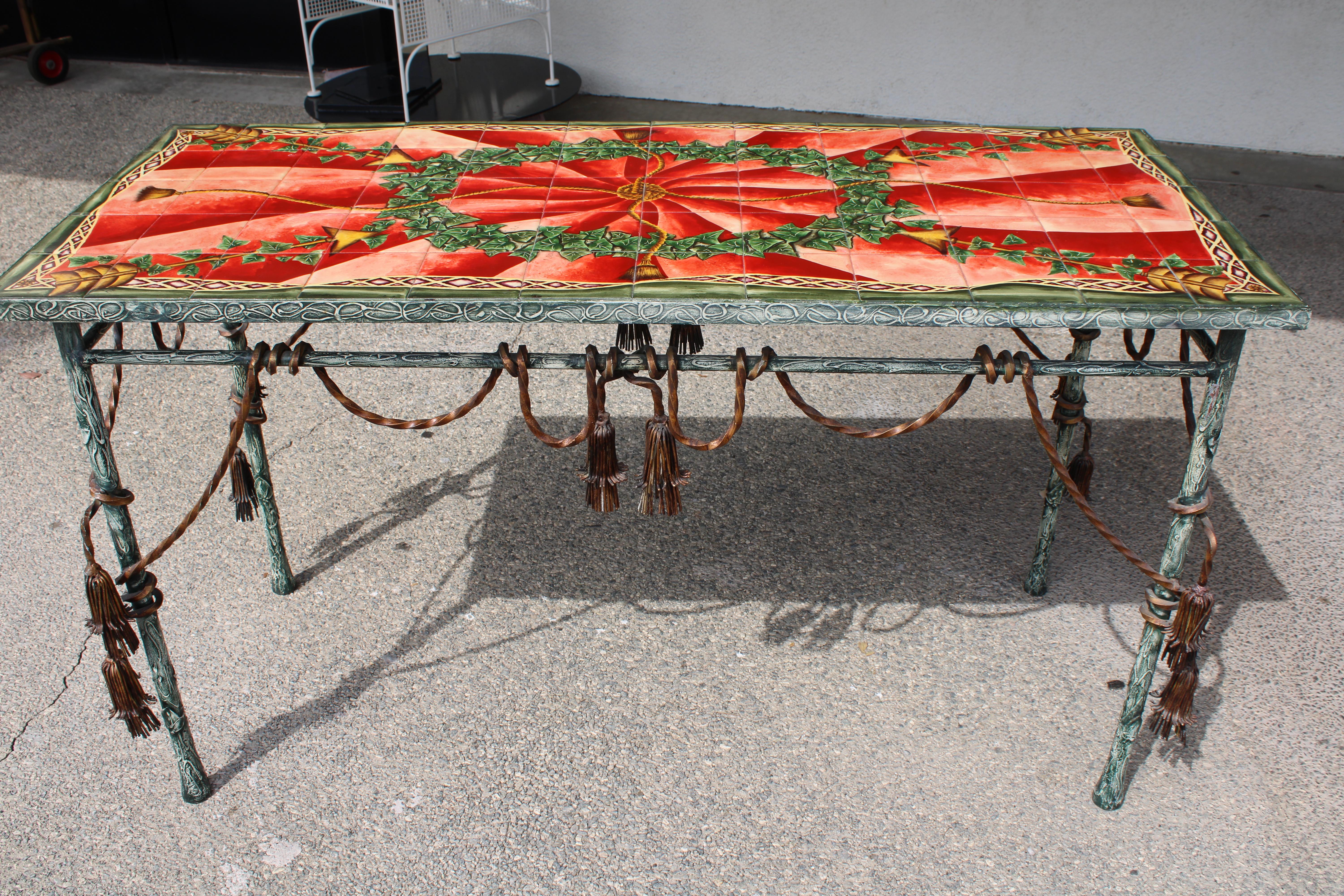 A Modern Italian style patinated metal and polychrome console table, having a rectangular top with hand painted glazed ceramic tiles depicting ivy garlands and arrows. The patinated base with leaf form legs and tassels surround the table base. Table