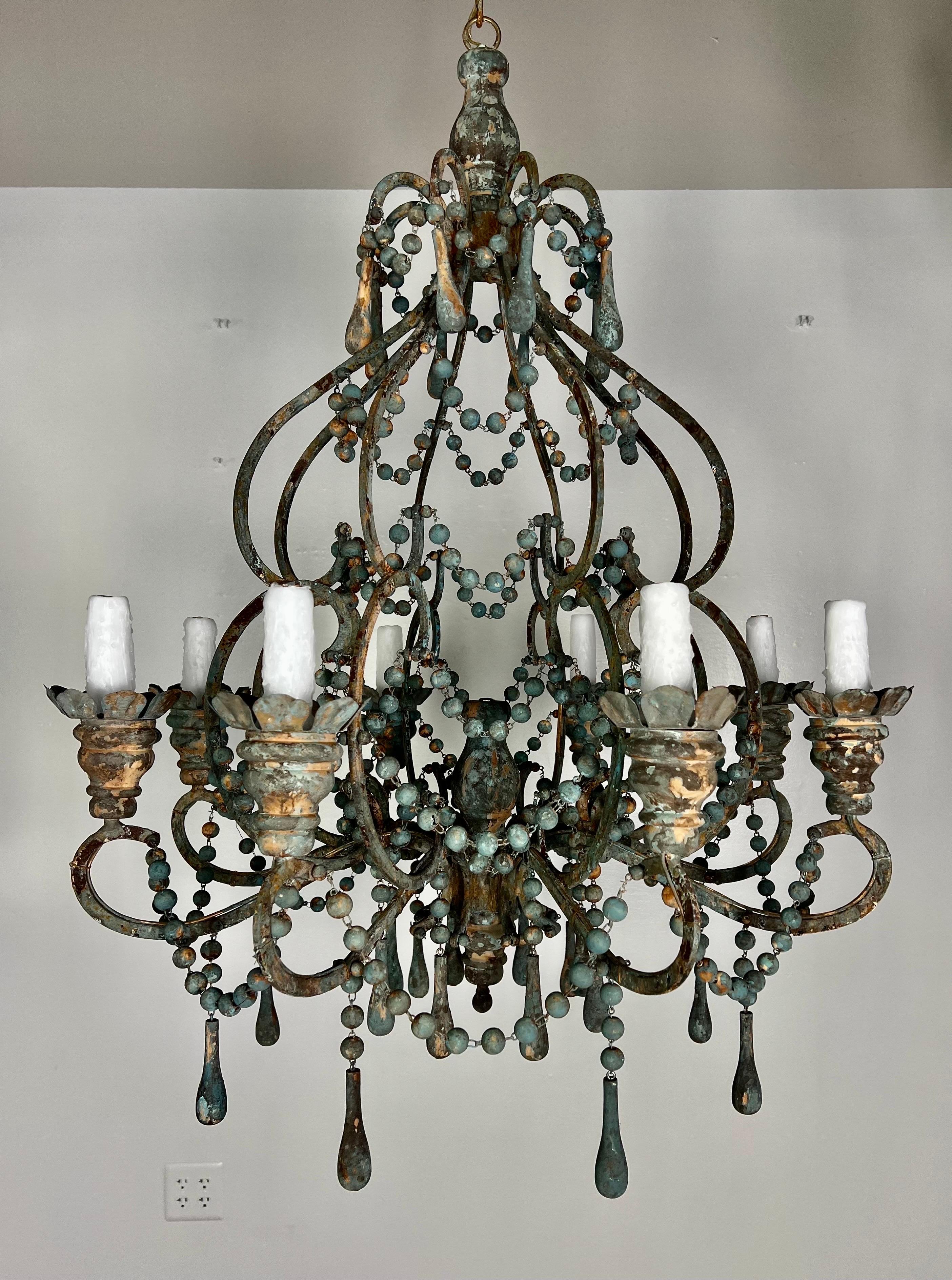 Lustre personnalisé à huit lumières de style italien avec des guirlandes de perles peintes et des gouttes de bois vintage. Le lustre est peint en bleu acier antique avec des touches d'or et de rouille. Les huit luminaires ont été refaits avec des