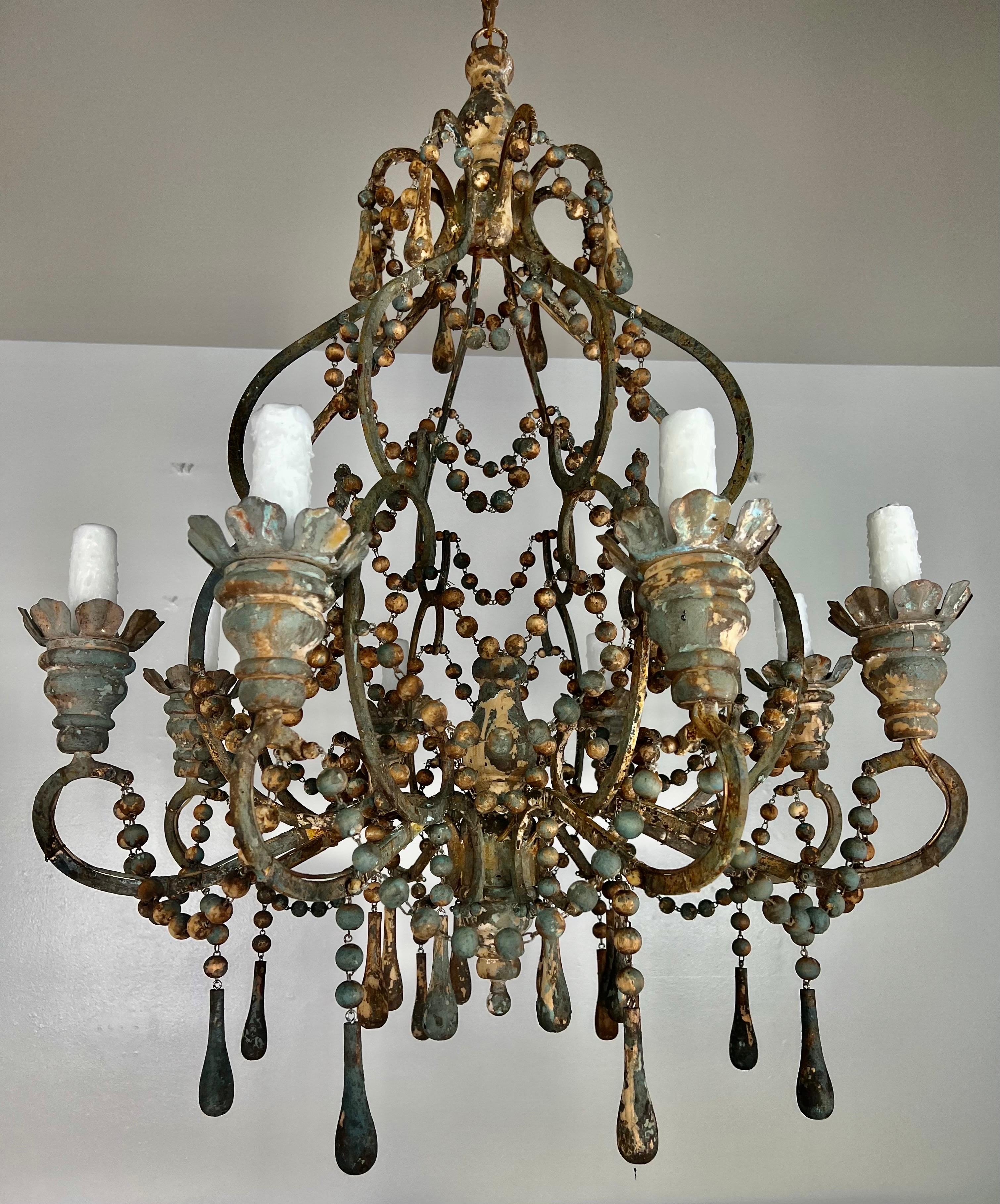 Custom Eight light Italian style wood & Iron Painted Chandelier by Melissa Levinson. Blue, gold, and cream can be seen throughout the chandelier. the fixture is newly wired with drip wax candle covers. Includes chain & canopy.