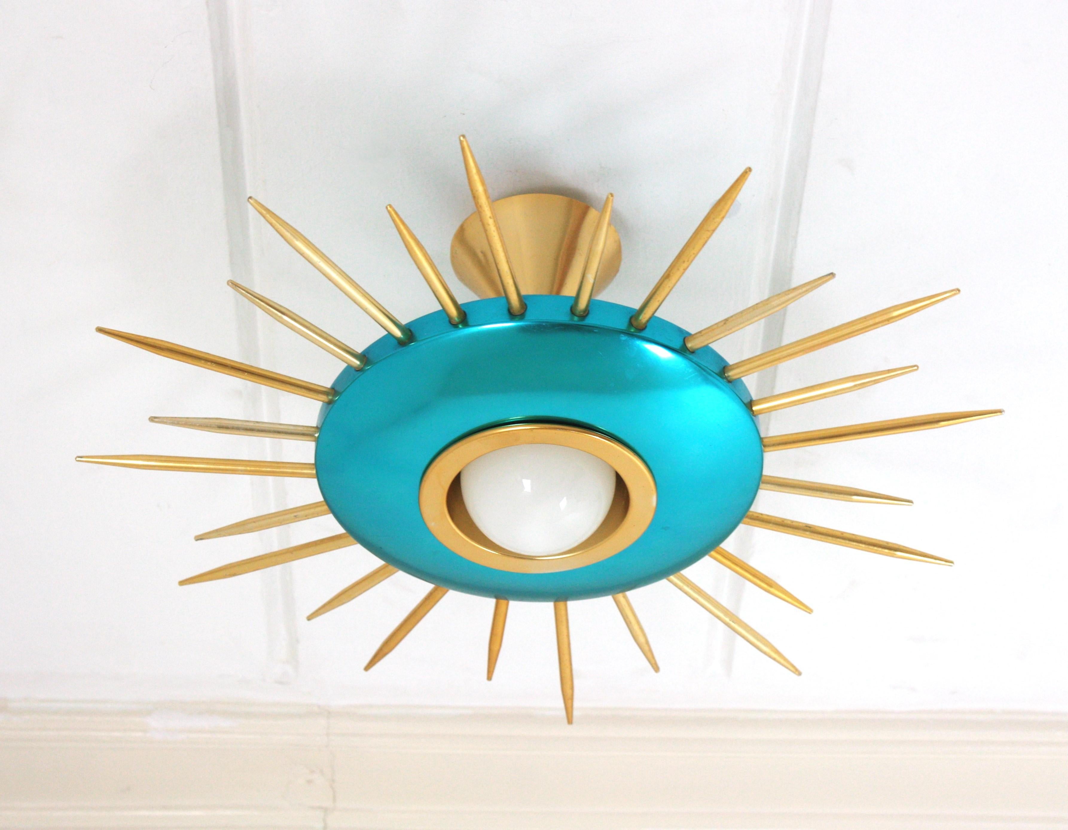Lámpara colgante de montaje empotrado de metal azul y rayos de sol dorados, moderna de mediados de siglo. Italia, años 50.
Esta llamativa lámpara de techo presenta una pantalla metálica azul rodeada de gruesos rayos de metal dorado en dos tamaños.