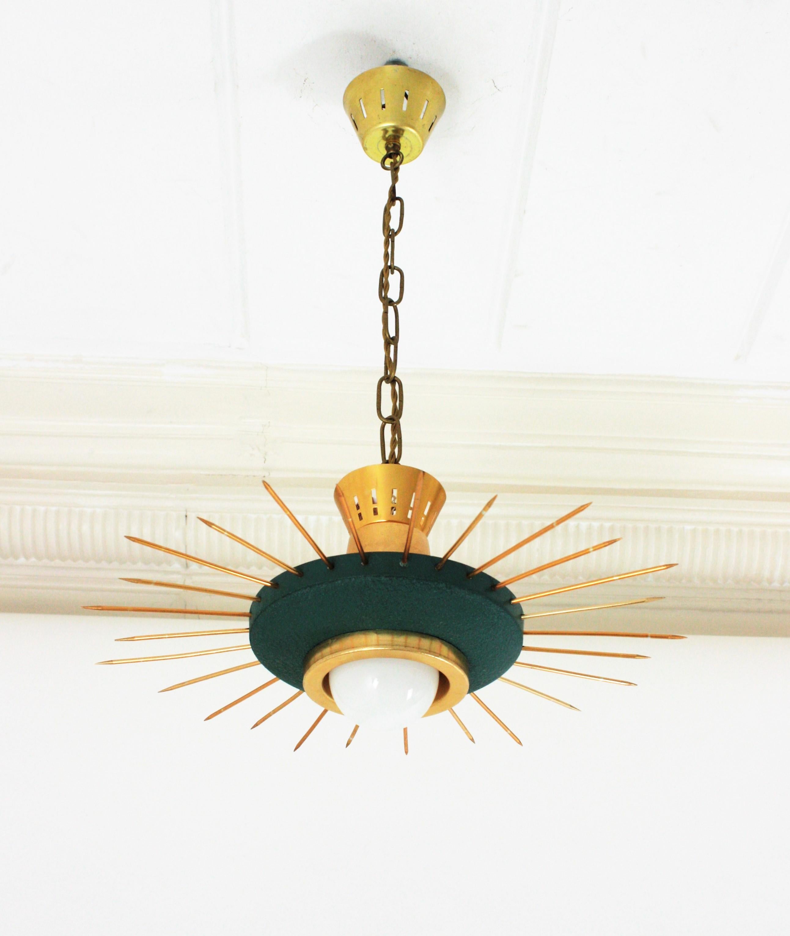 Mid-Century Modern green lacquered metal and brass sunburst suspension light, chandelier or light fixture, Italy, 1950s.
This eye-catching sunburst ceiling lamp features a green metal shade surrounded by brass spikes. It hangs from a brass chain