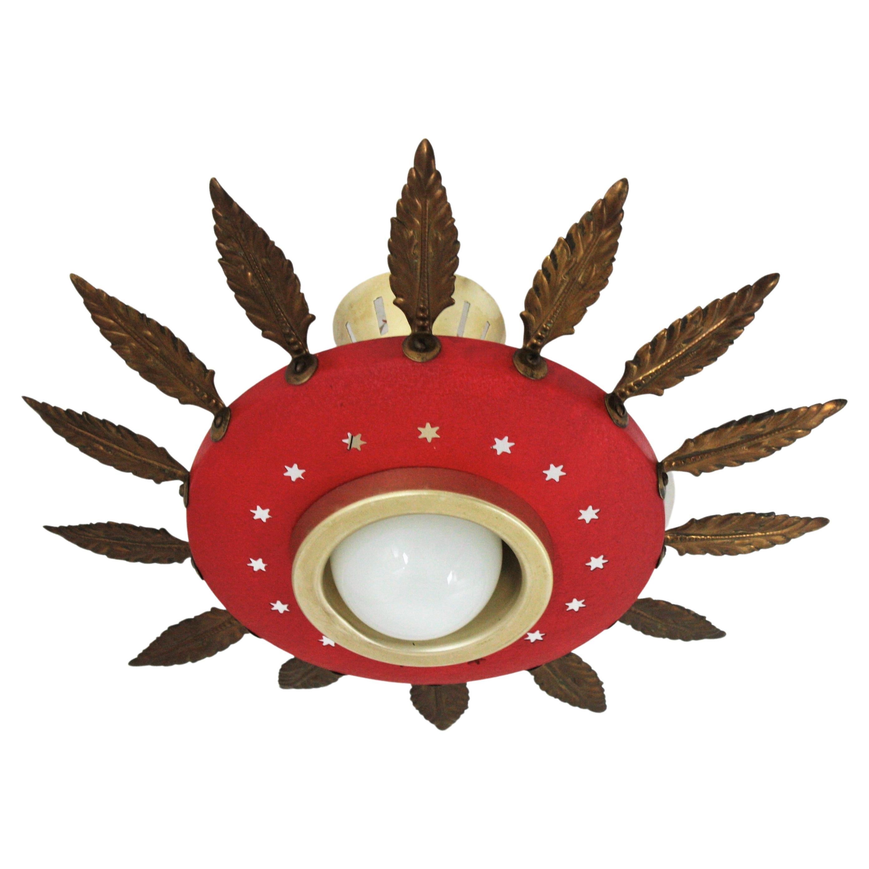 Mid-Century Modern red lacquered metal and brass sunburst suspension light, chandelier or light fixture. Italy, 1950s.
This eye-catching ceiling lamp features a red lacquered metal shade adorned by star shaped perforations. It is surrounded by