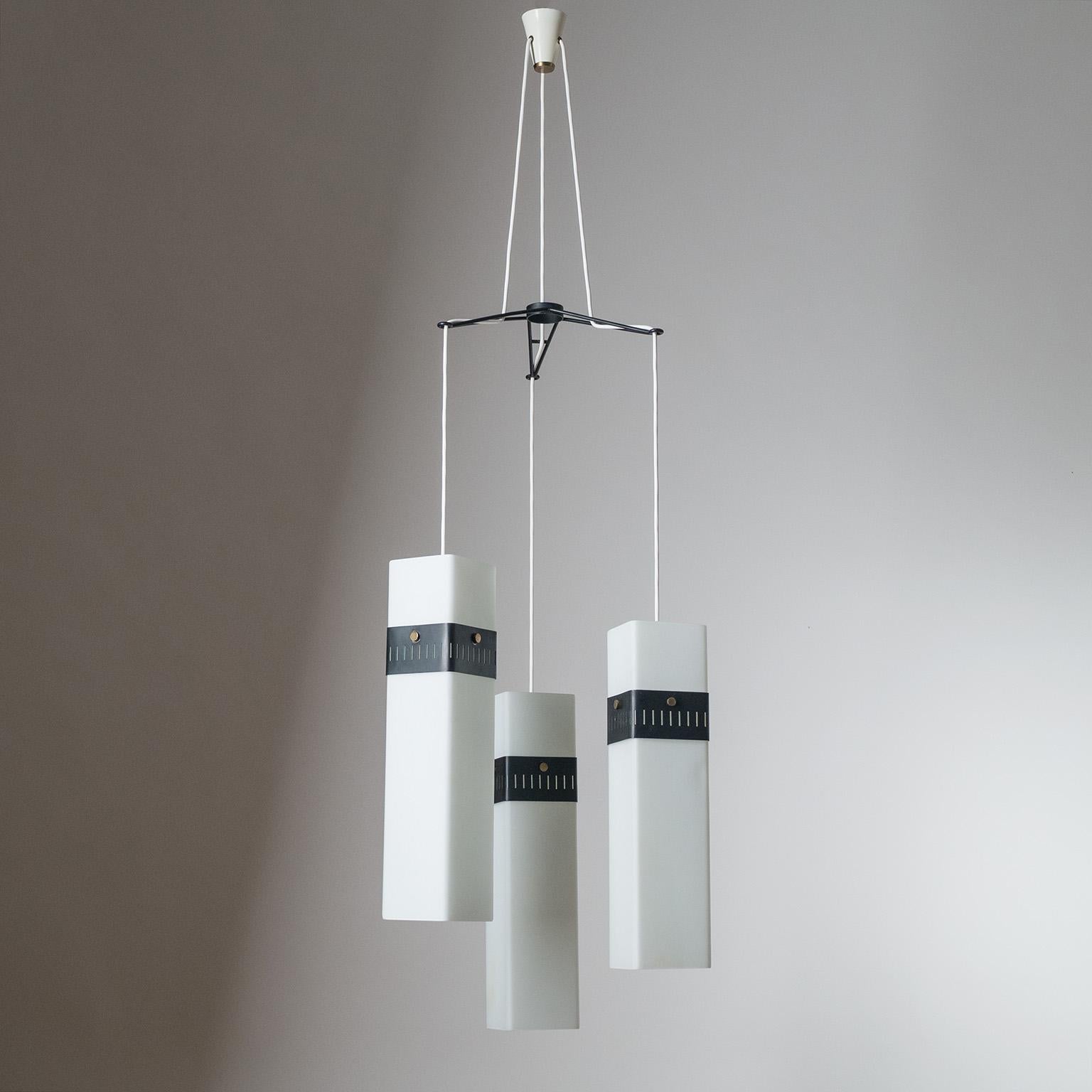 Rare Italian suspension chandelier from the 1950s. Three long square 'triplex opal' satin glass diffusers - circa 17inches/43cm, each slightly different - are suspended from a filigrane black steel structure. Three original brass and ceramic sockets