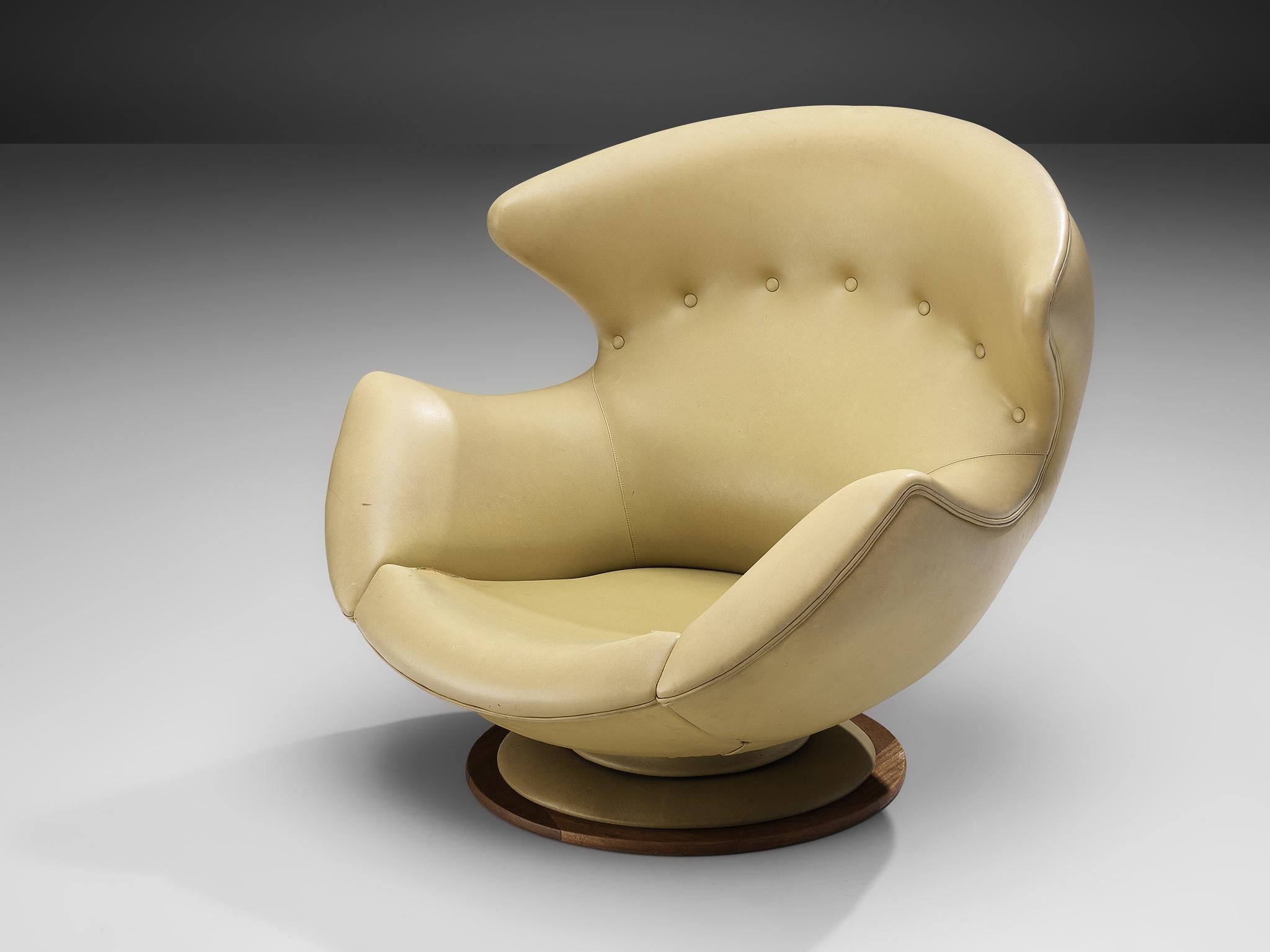 Lounge chair, leatherette, wood, Italy, 1970s

Large and comfortable winged lounge chair in yellow faux-leather upholstery. The rounded overall shape of the easy chair, with the wings reaching towards the armrests, makes sure that the chair almost