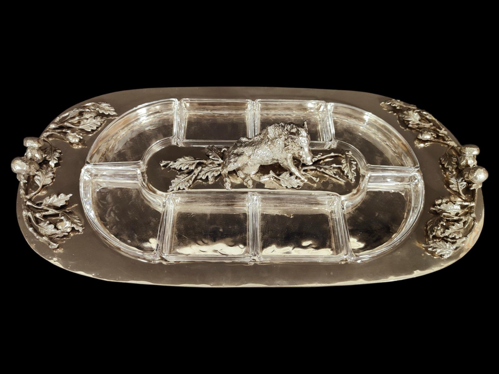 Italian table center surtout from the 70s
Elegant centerpiece from the 70s in silver metal made in Italy.In the center is a reclining wild boar and on the edges it is decorated with leaves and arbutus fruits.Measures: 70x35x20 cm