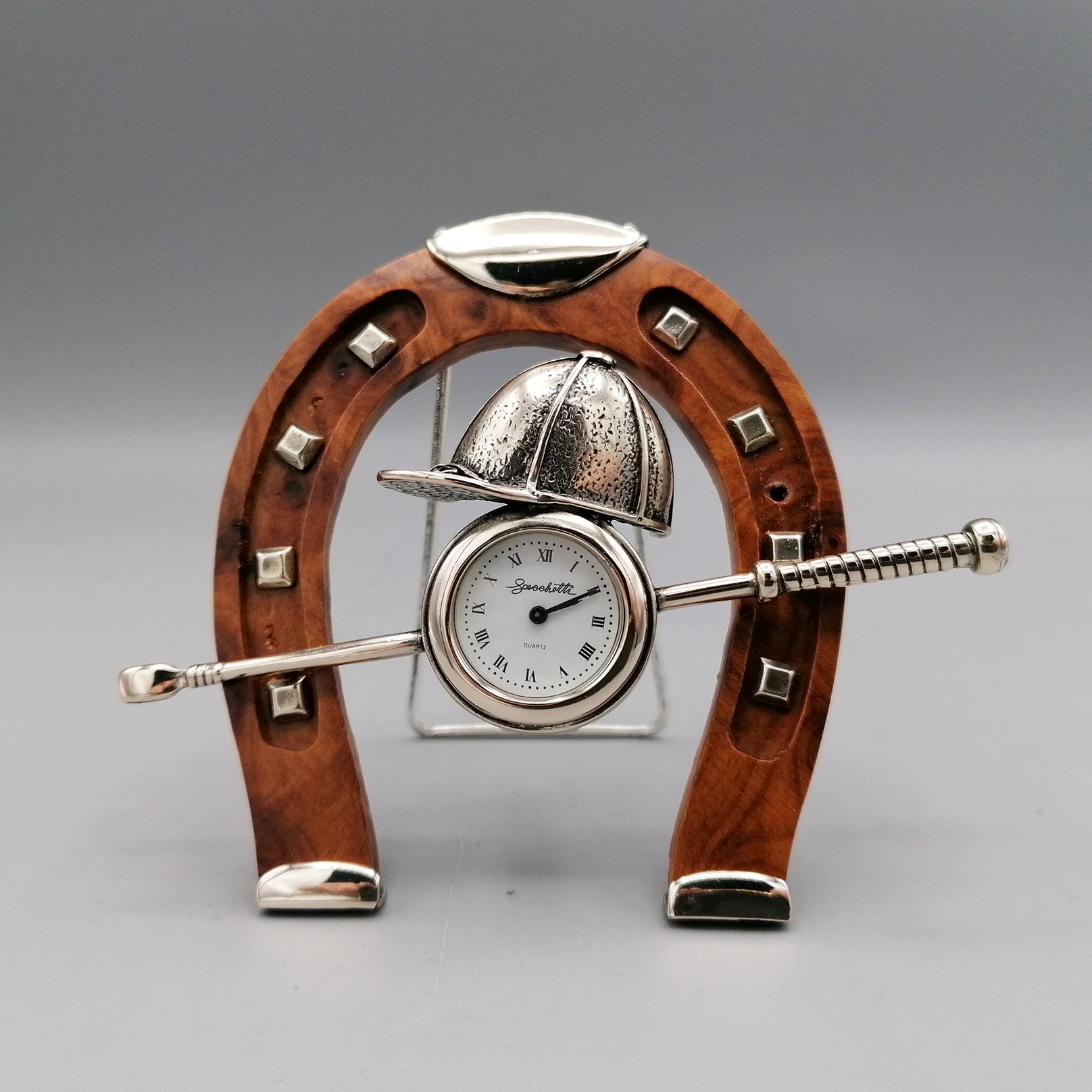 Table clock in 800 silver and wood depicting polo game equipment.
The bat and polo hat are part of the watch. 
The briar horseshoe has silver details on the base and top.
The back support is also in silver.
 