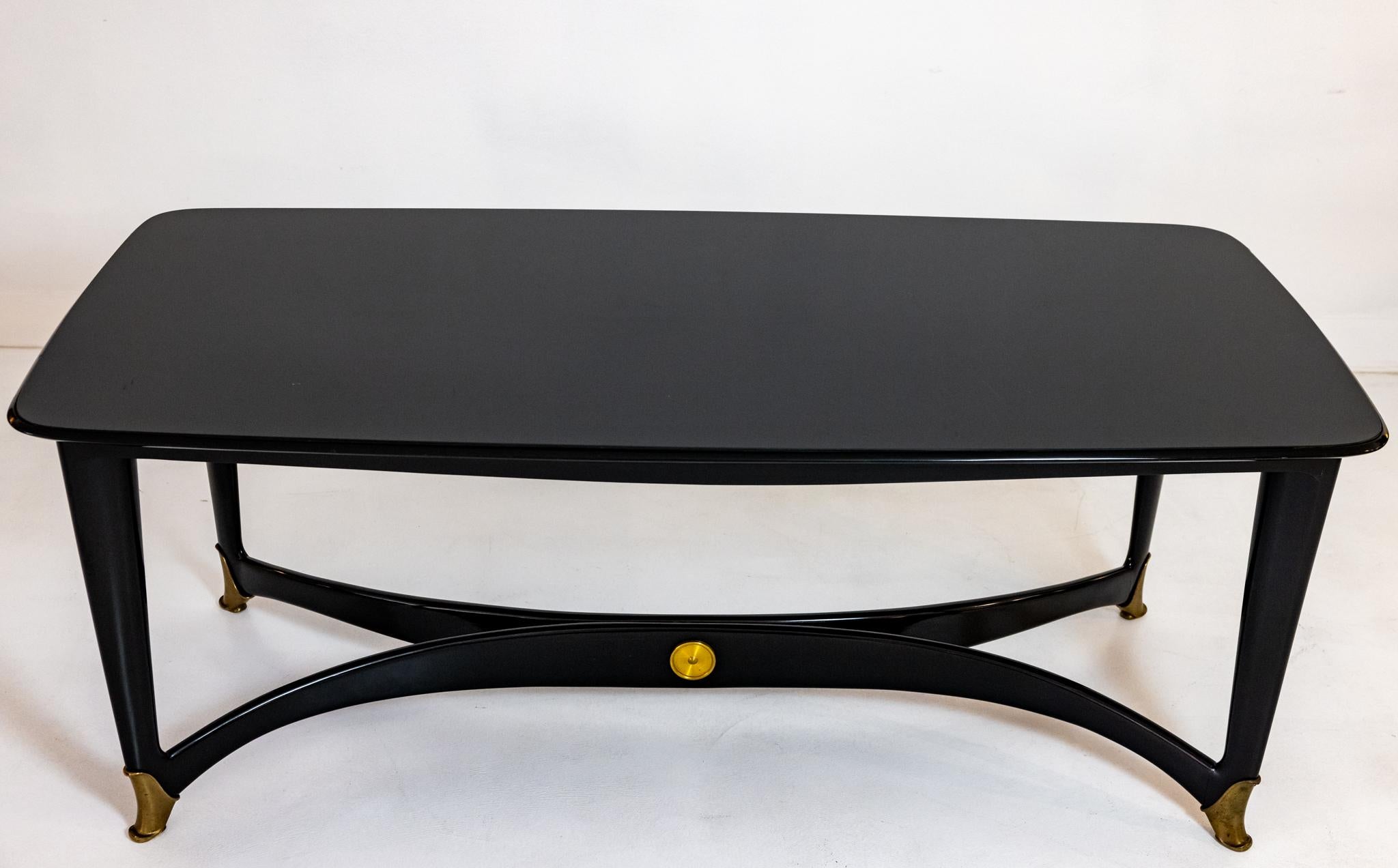 A wonderful example of Italian design. This table is composed of lacquered wood, black glass top, and brass accents. It would make a wonderful desk as seen in the last photo. In very fine original condition.