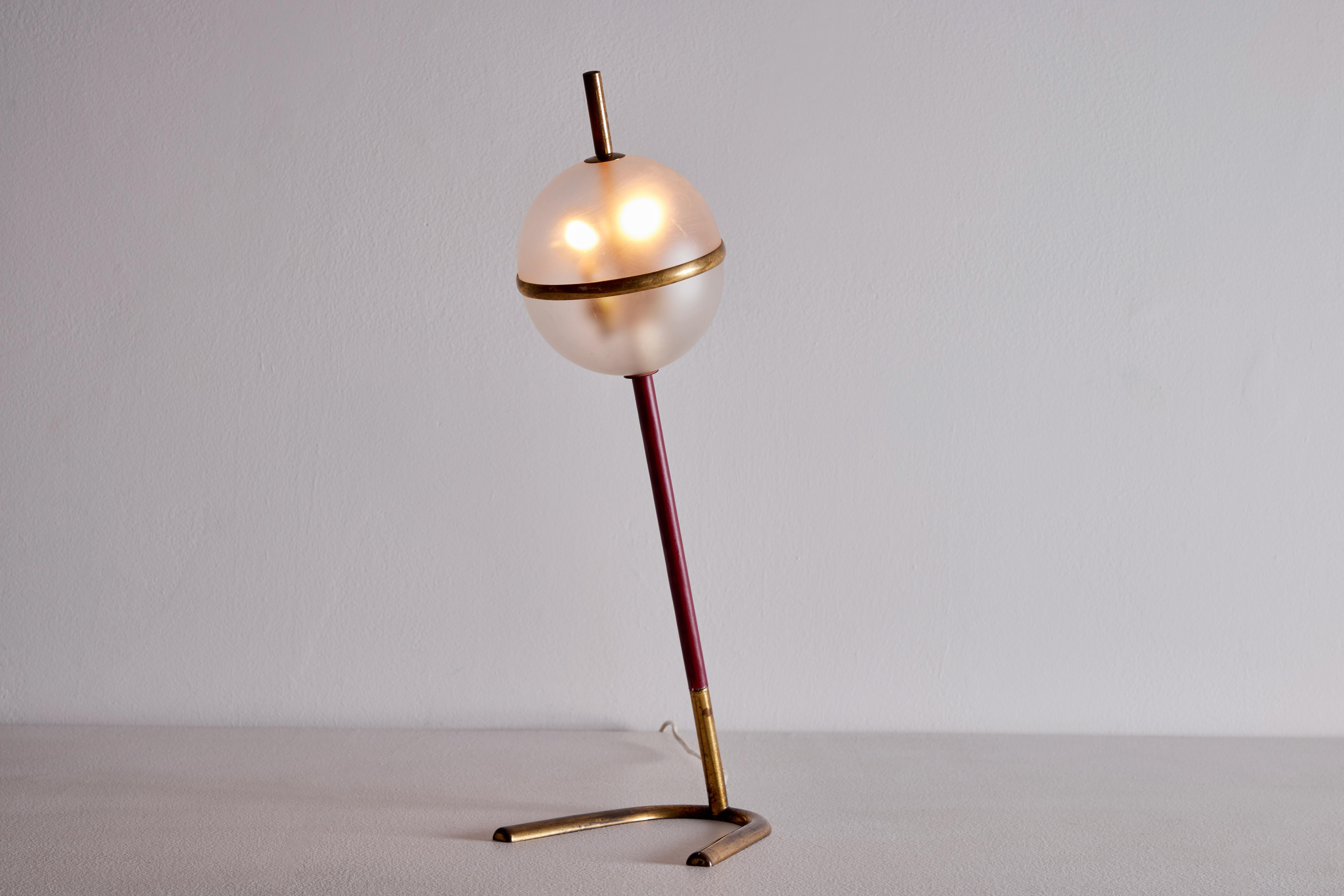 Table lamp manufactured in Italy, circa 1950's by Arredoluce. Brass, leather, glass diffuser. Original European cord. We recommend two E12 candelabra bulbs. Bulbs provided as a one time courtesy. Diameter in measurement is for base of lamp.