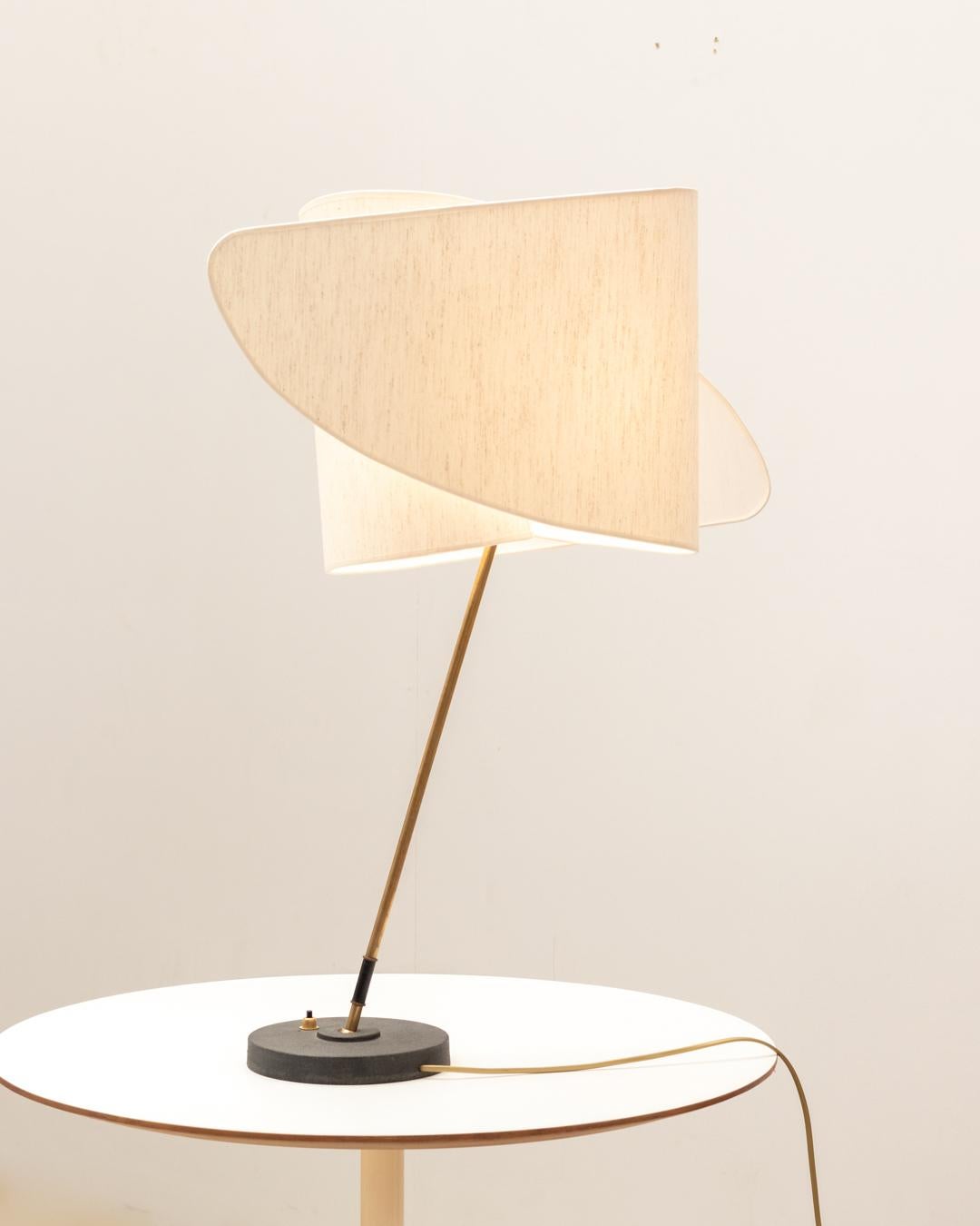 Lampe de table italienne avec un abat-jour caractéristique rappelant les créations de Carlo Mollino. L'abat-jour est soutenu par un bras rotatif en laiton et une base en métal noir.

En très bon état d'origine.

N'hésitez pas à nous contacter pour