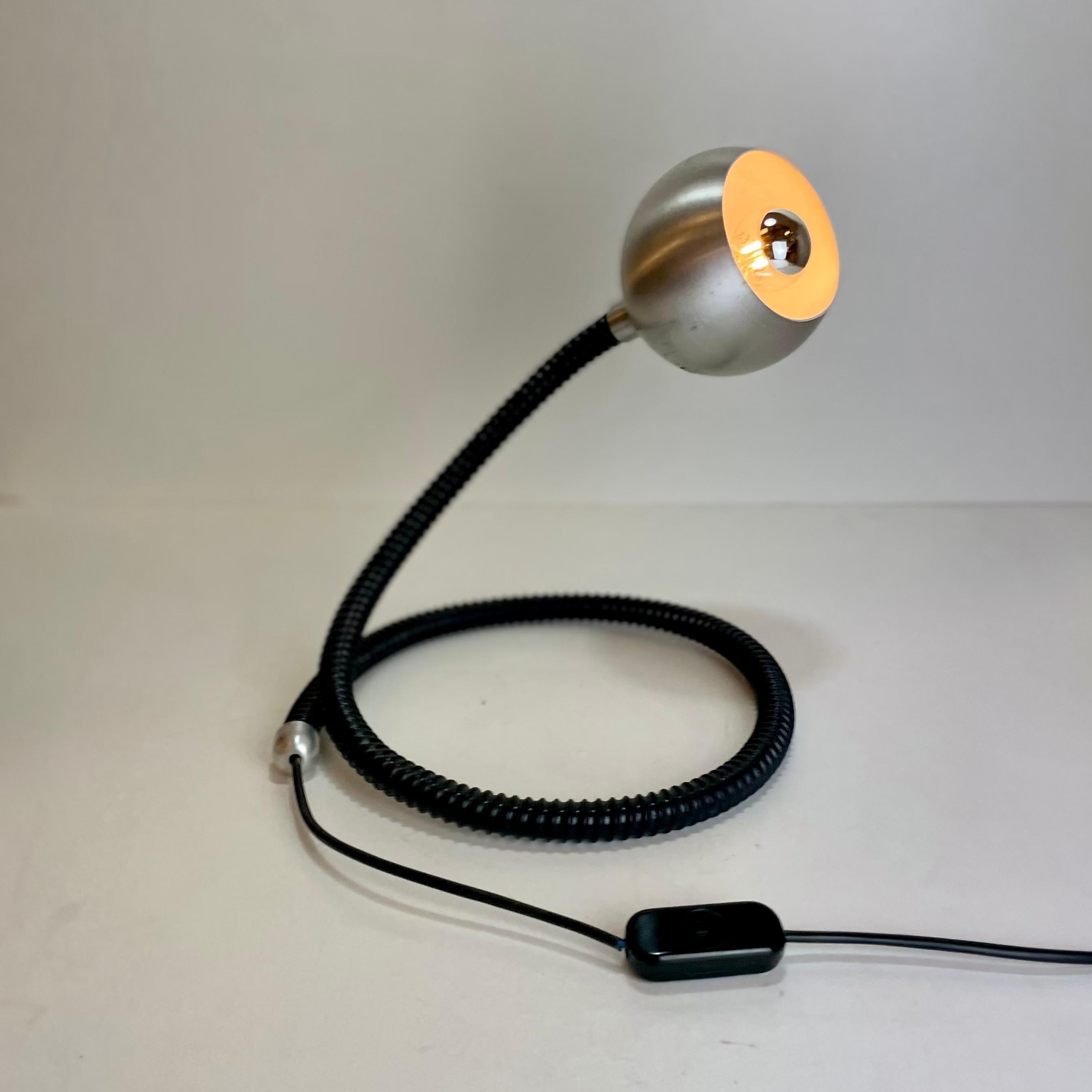 Italian flexible table lamp in the style of the Hebi lamp designed by Isso Hosoe for Valenti in the 1970s.
Adjustable to your desires, this snake lamp is made in black caterpillar plastic tube with a brushed stainless steel lamp shade.

In the style