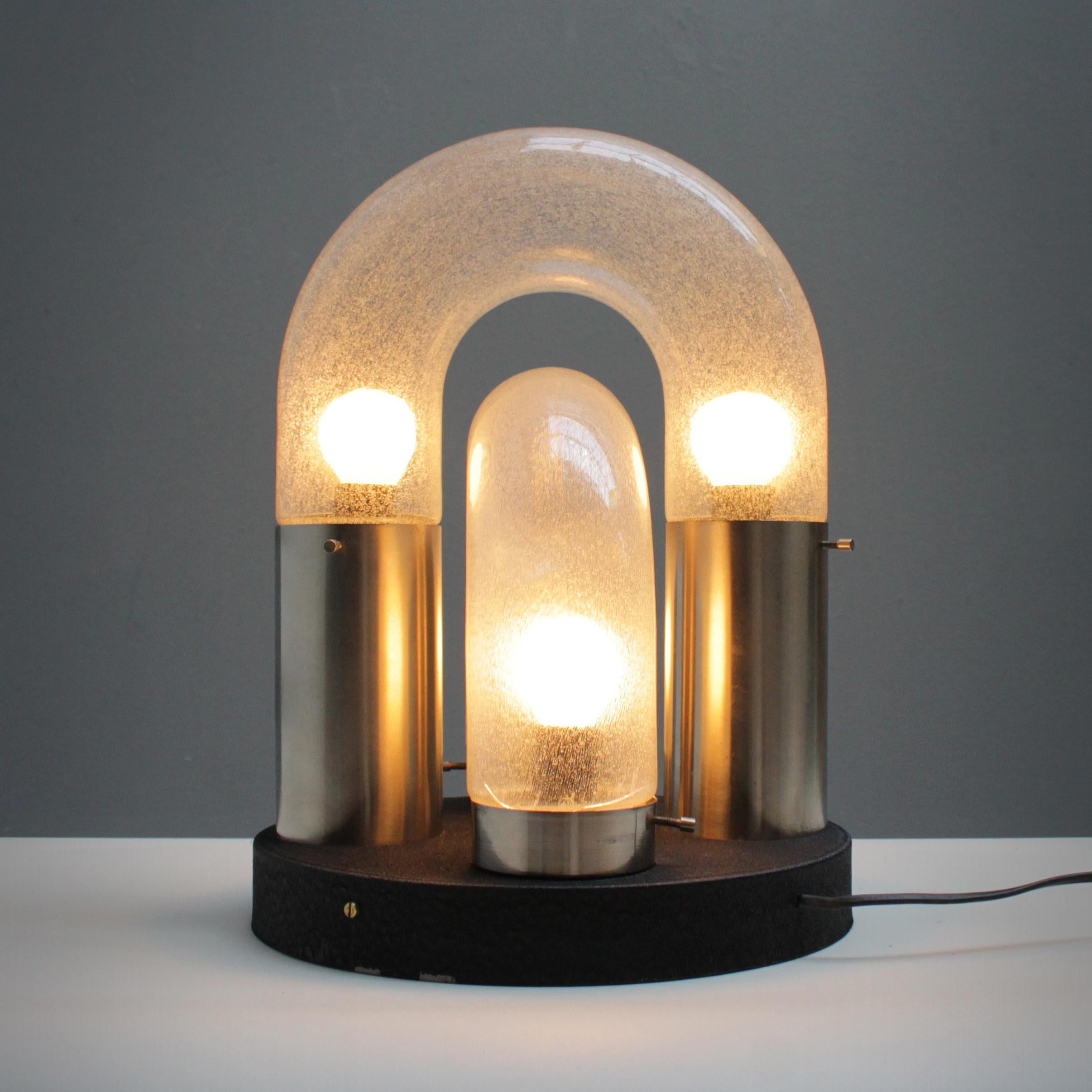 Table light by Carlo Nason and manufactured in the 1960s by Mazzega, Italy. Two curved glass tubes of Murano glass. Metal base with black crackled lacquer and chrome holders.
Four bulbs (E17 14-17 mm), small Edison screw (SES) of max 40 watt, the