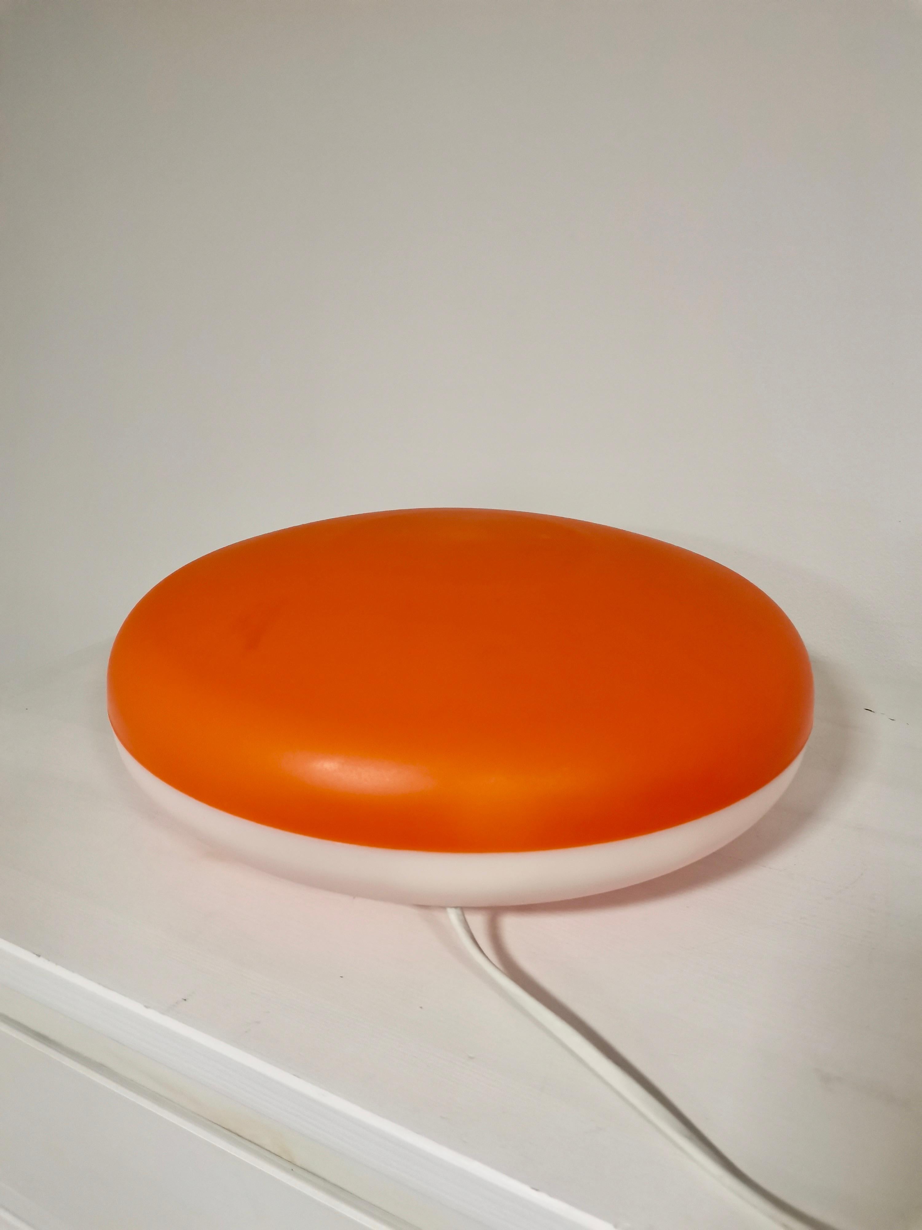 Lamp by producer Cosi Come Designed by Protocol Paris 1975-2000. Beautiful round lamp, orange at the top and white at the bottom. Can be used as a table lamp or wall lamp. With on and off button on the cable. With its warm light creates sensation of