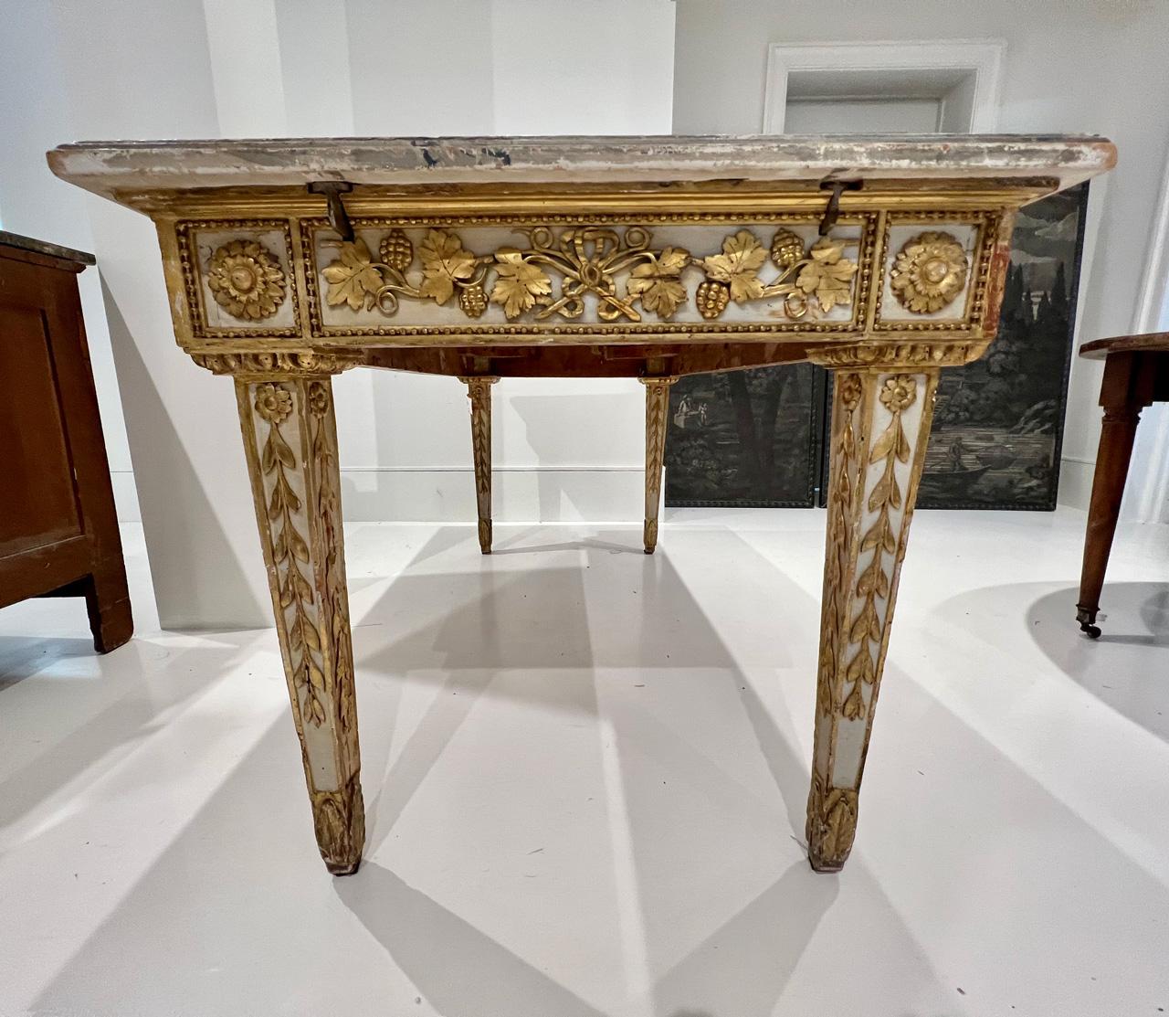 More is more with this stunning table. The aprons and legs are lavishly carved and gilded with a pale grey background. No surface on this amazing piece is left unadorned. The top and additional leaves are expertly painted a bold faux marble. The