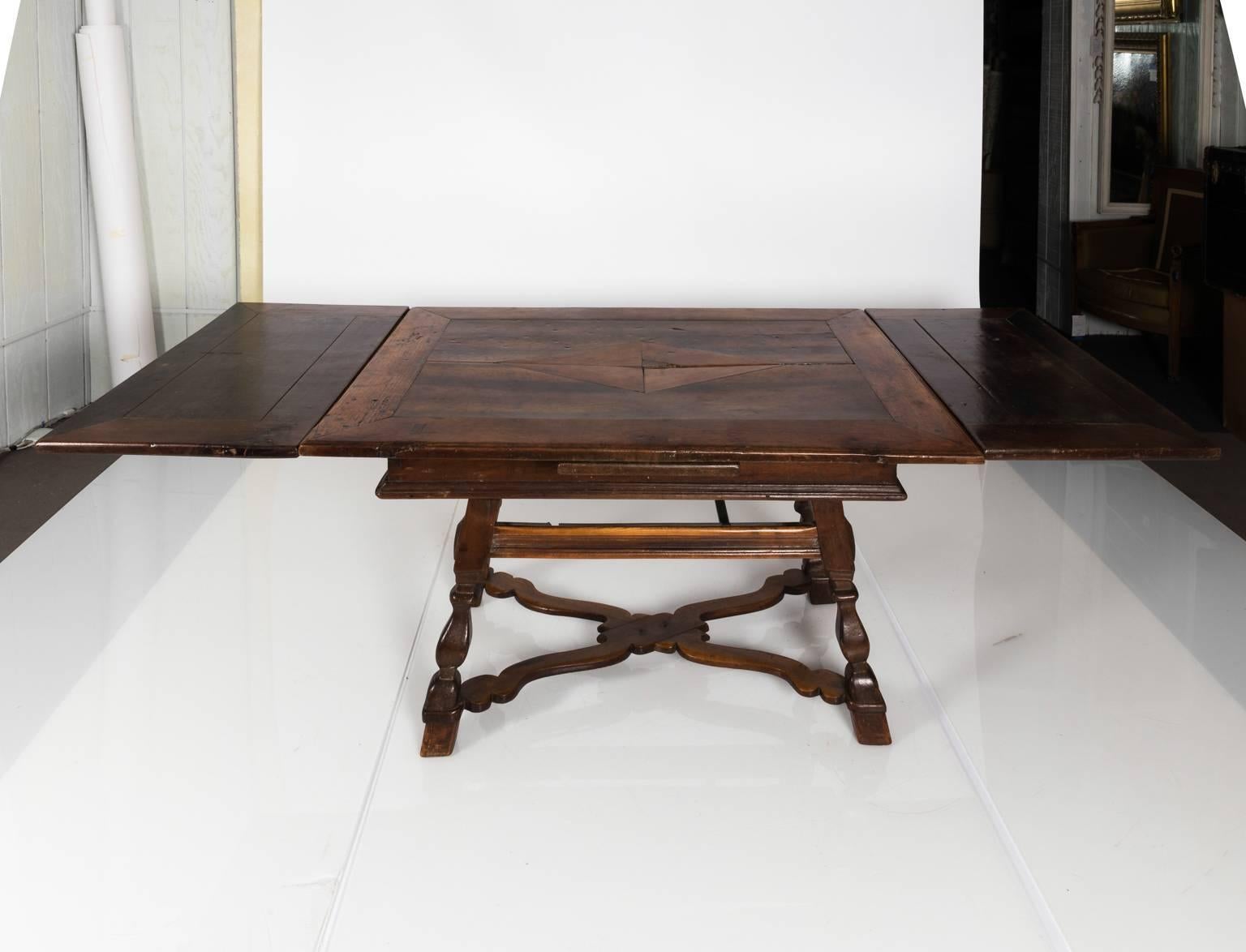 Italian table with one drawer and an X-shaped cross stretcher, circa early 20th century. The tabletop also features a starburst pattern with two leaves.
 