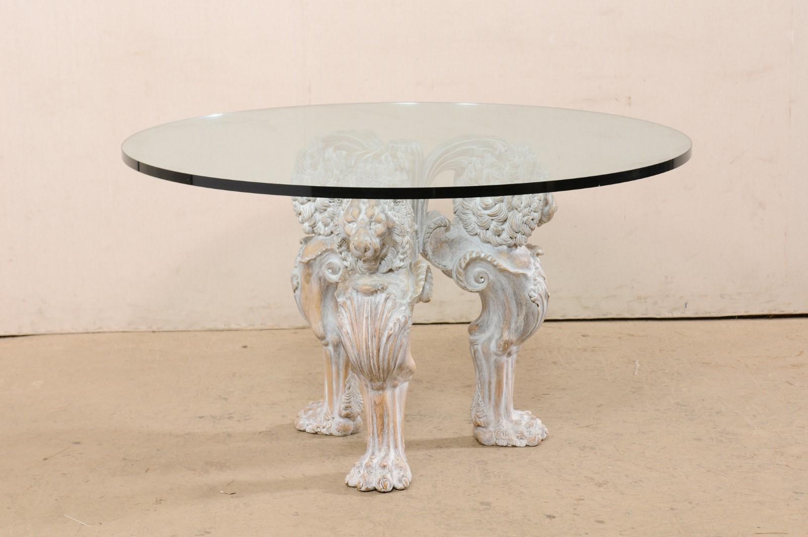 An Italian glass top dining table with lion motif carved base. This vintage table from Italy is topped with a 52