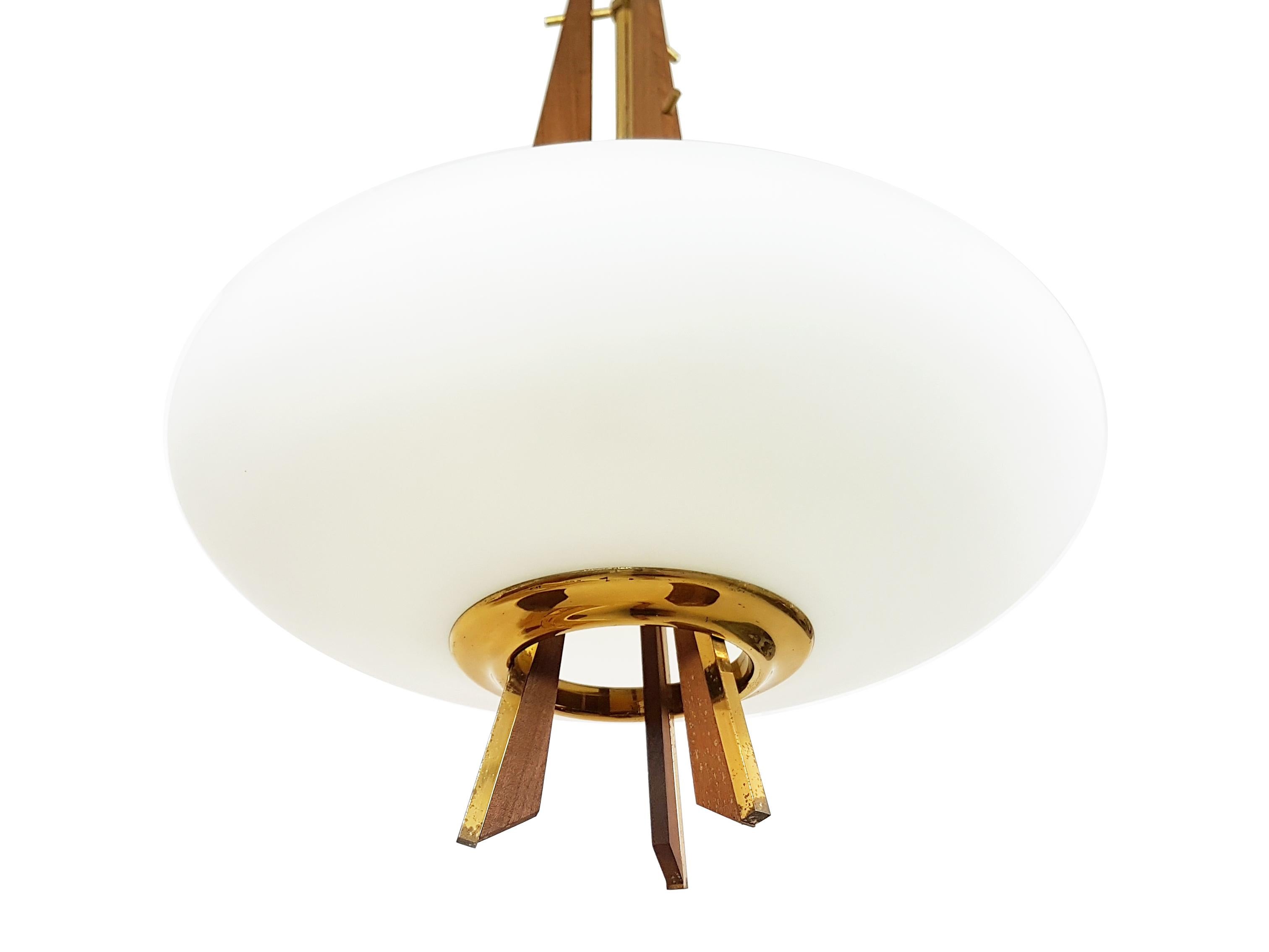 This beautiful suspension lamp was produced in Italy, circa 1960. It is made with a brass structure with decorative teak elements and a white elliptical opal glass shade. Very good condition: only a small chipping on the shadow near the small hole.