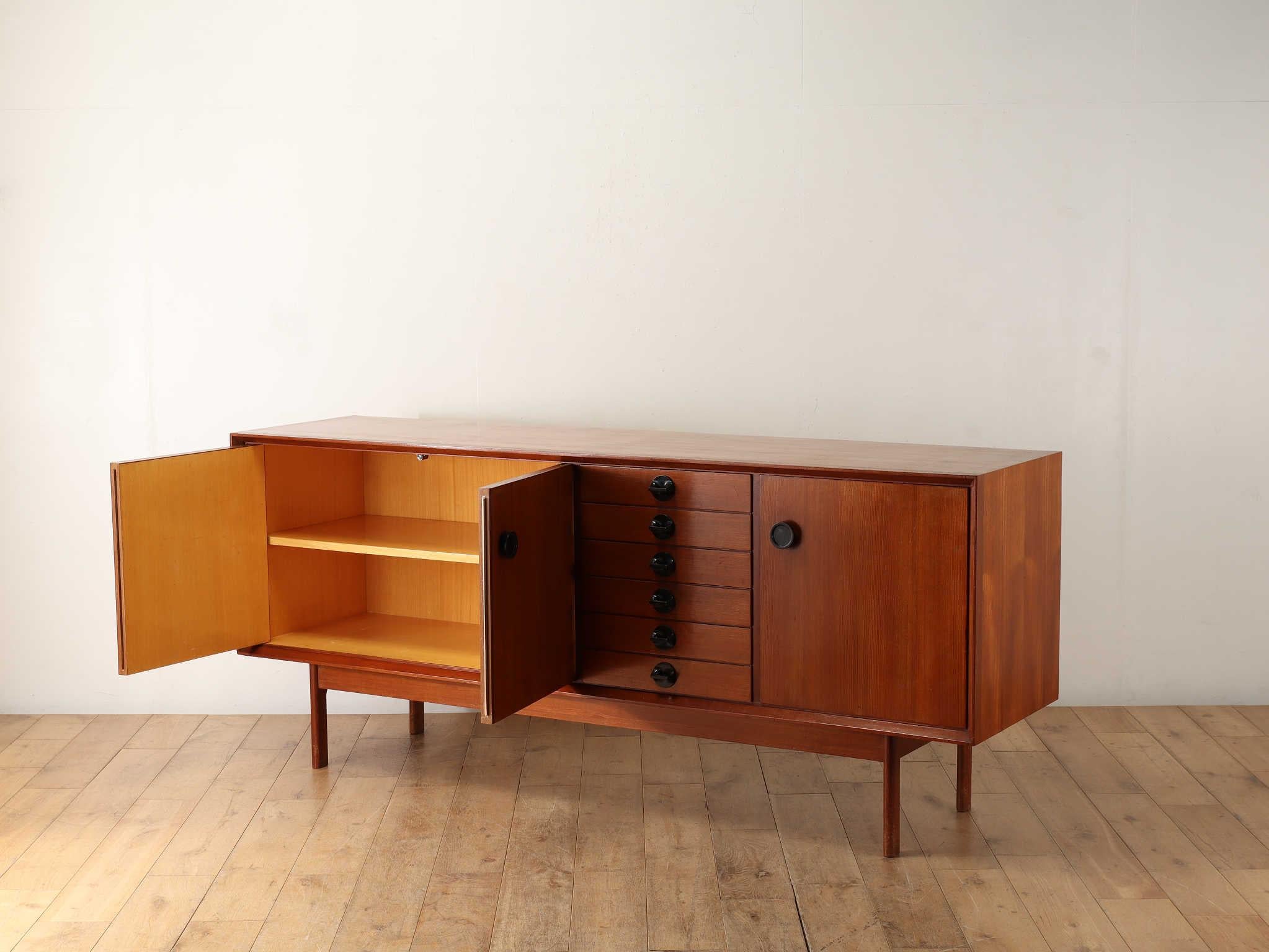 Buffet italien vintage.Impression de mode avec des tons de bois clair et une forme angulaire.Les pieds sont de simples colonnes élancées.Le corps large et les pieds fins sont une caractéristique attrayante du vintage italien.Les poignées sont un ton