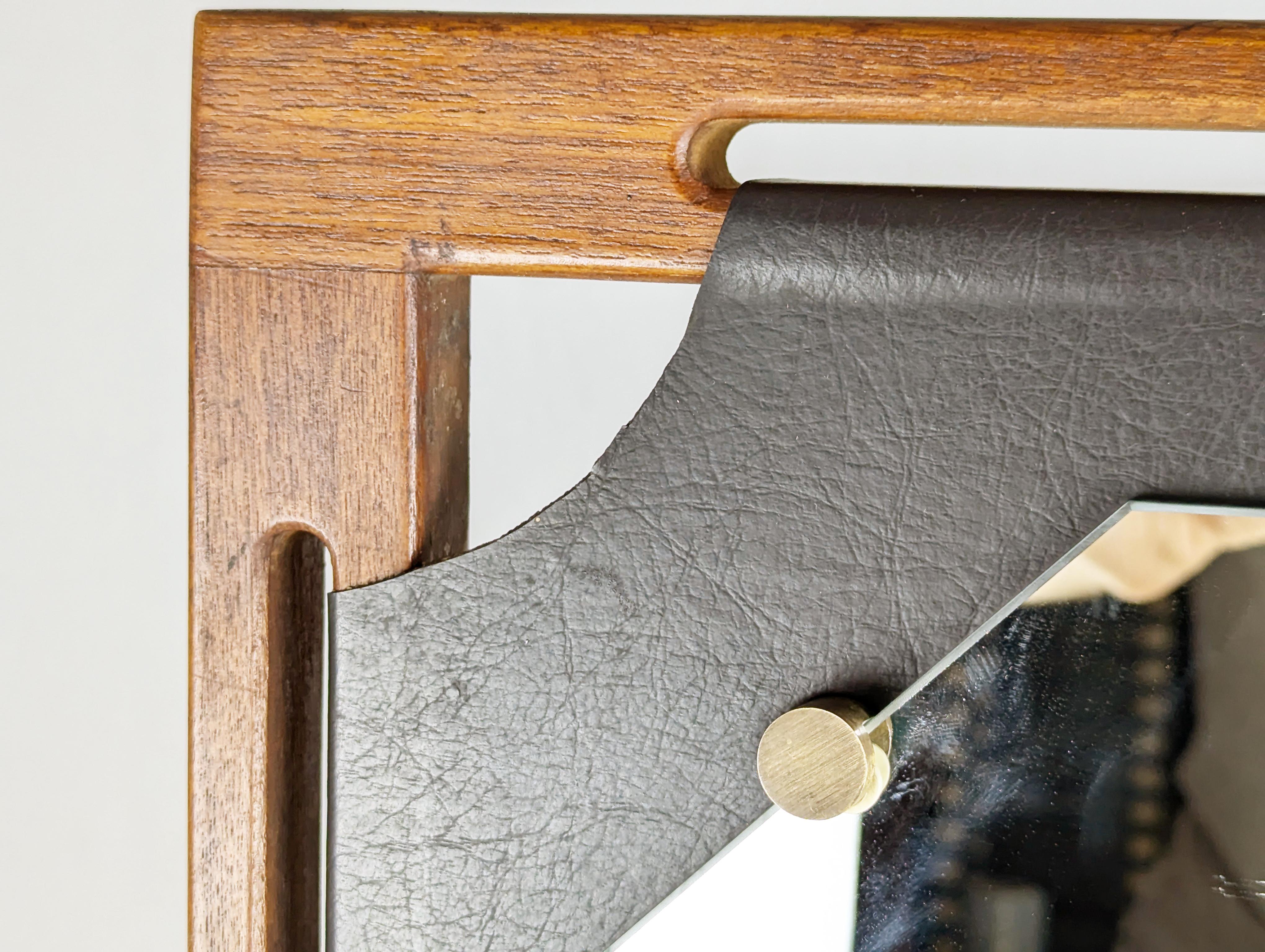 Unusual square wall mirror in teak wood, black skai and brass. The mirror, shaped at the corners, is fixed to the faux leather through the use of 4 brushed brass clips. The skai is stretched on the frame structure and blocked on the back.
The