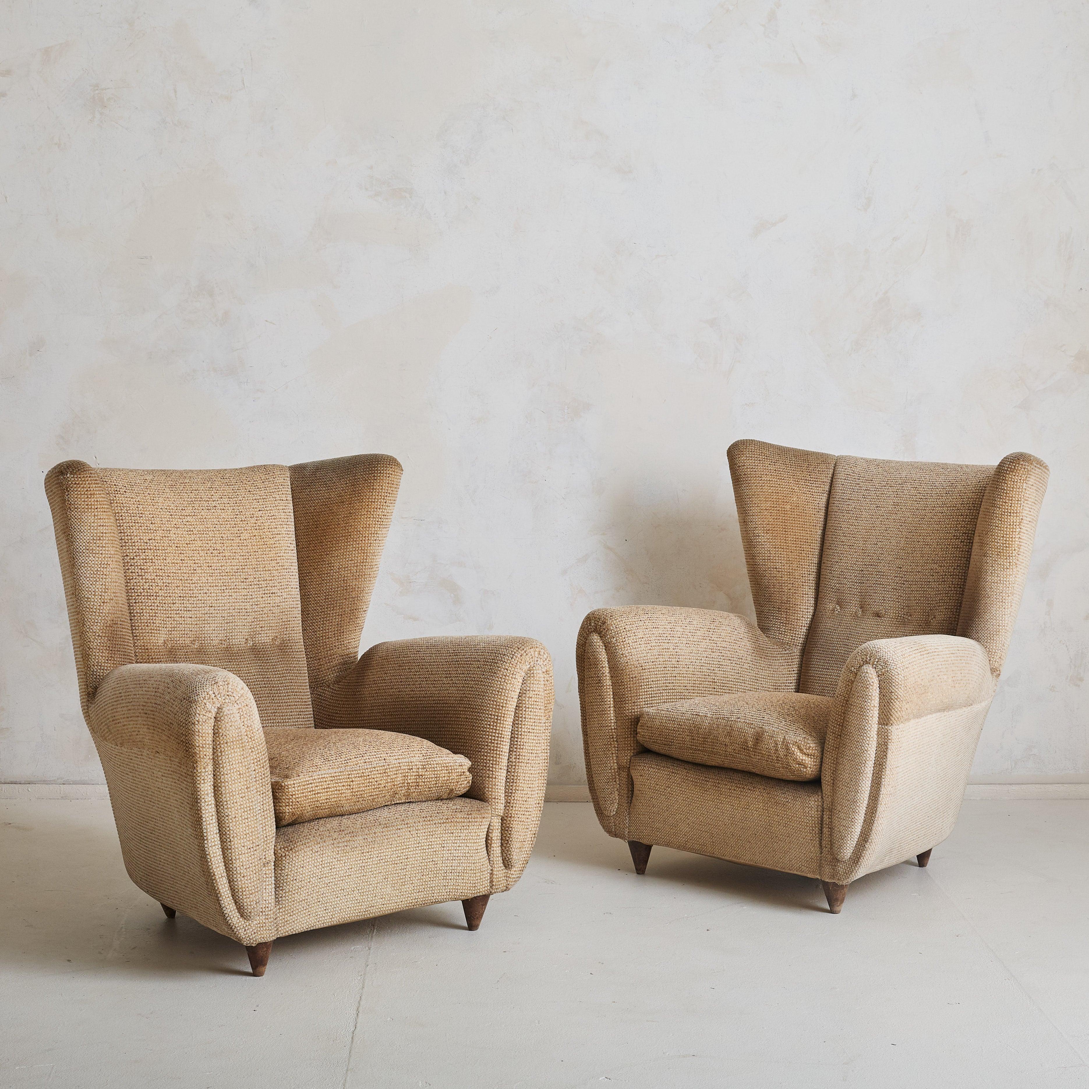 Sold and priced individually.  One sold, one available

A 1960s Italian teddy lounge chair featuring a dramatic, enveloping wingback and stately arms. It stands on tapered wooden legs, stained in a rich brown hue.  The seat cushion is down
