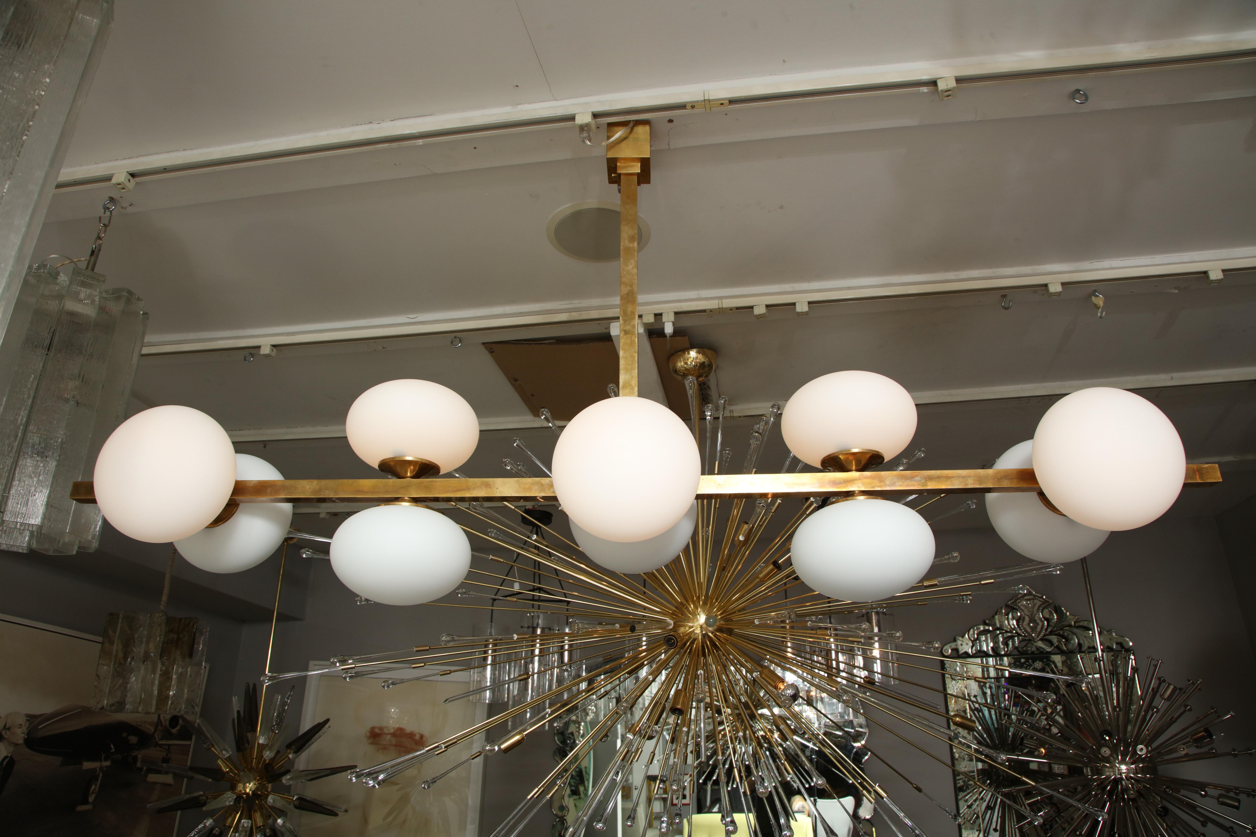 Ten elongated opaline glass globe chandelier with antique brass finish frame. Made to order.